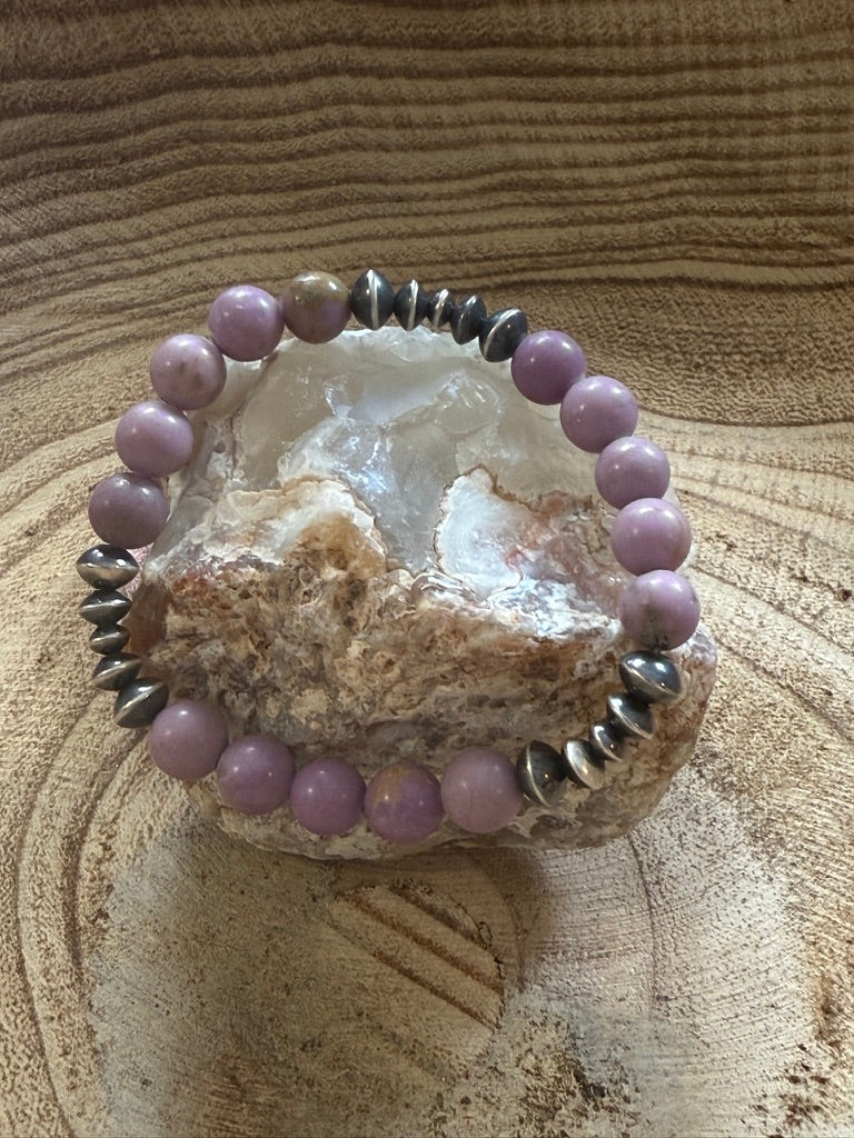 Purple beaded bracelet on a rough stone with a wooden background