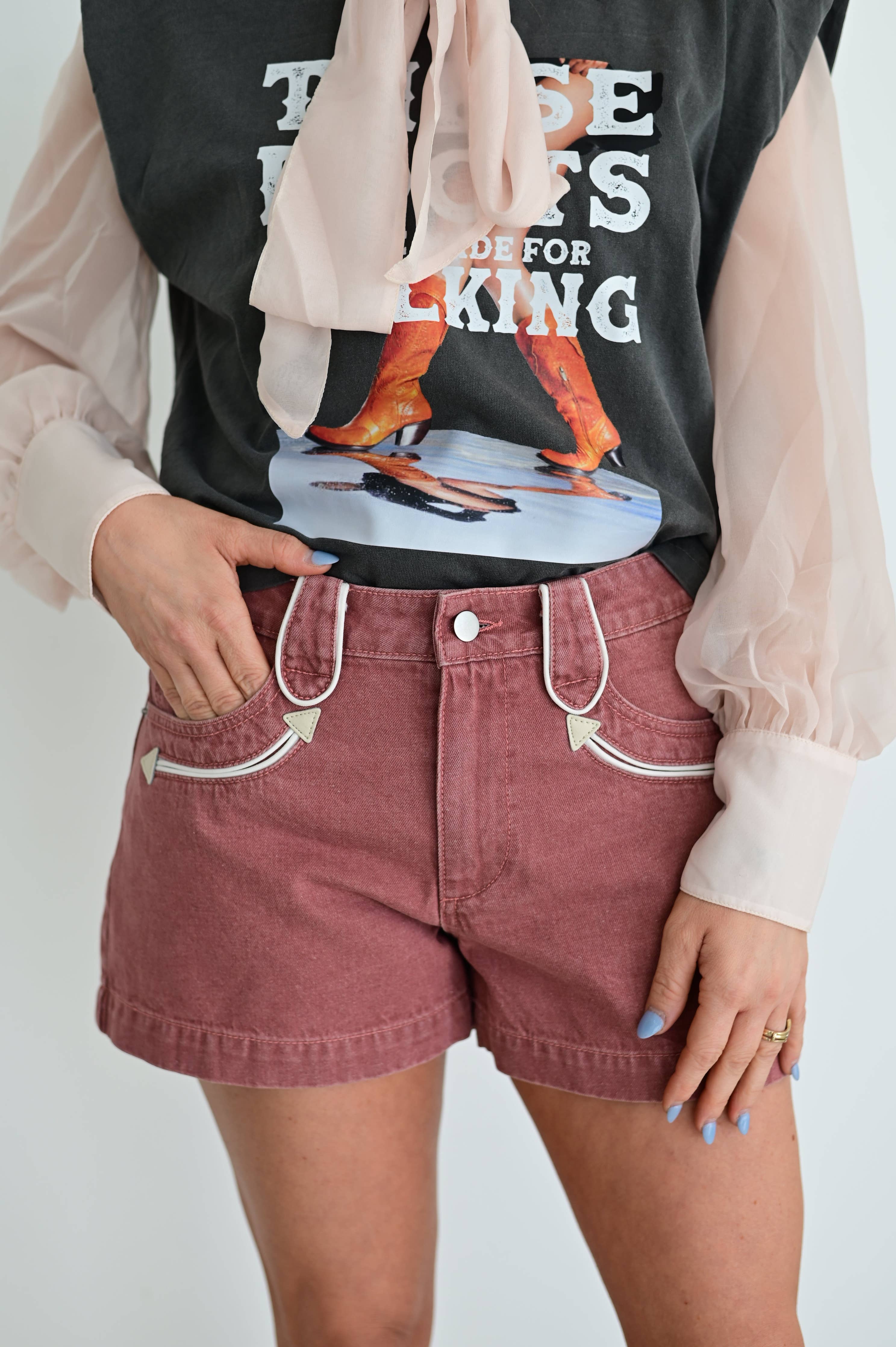 Person wearing a black graphic t-shirt and red shorts with a plain background