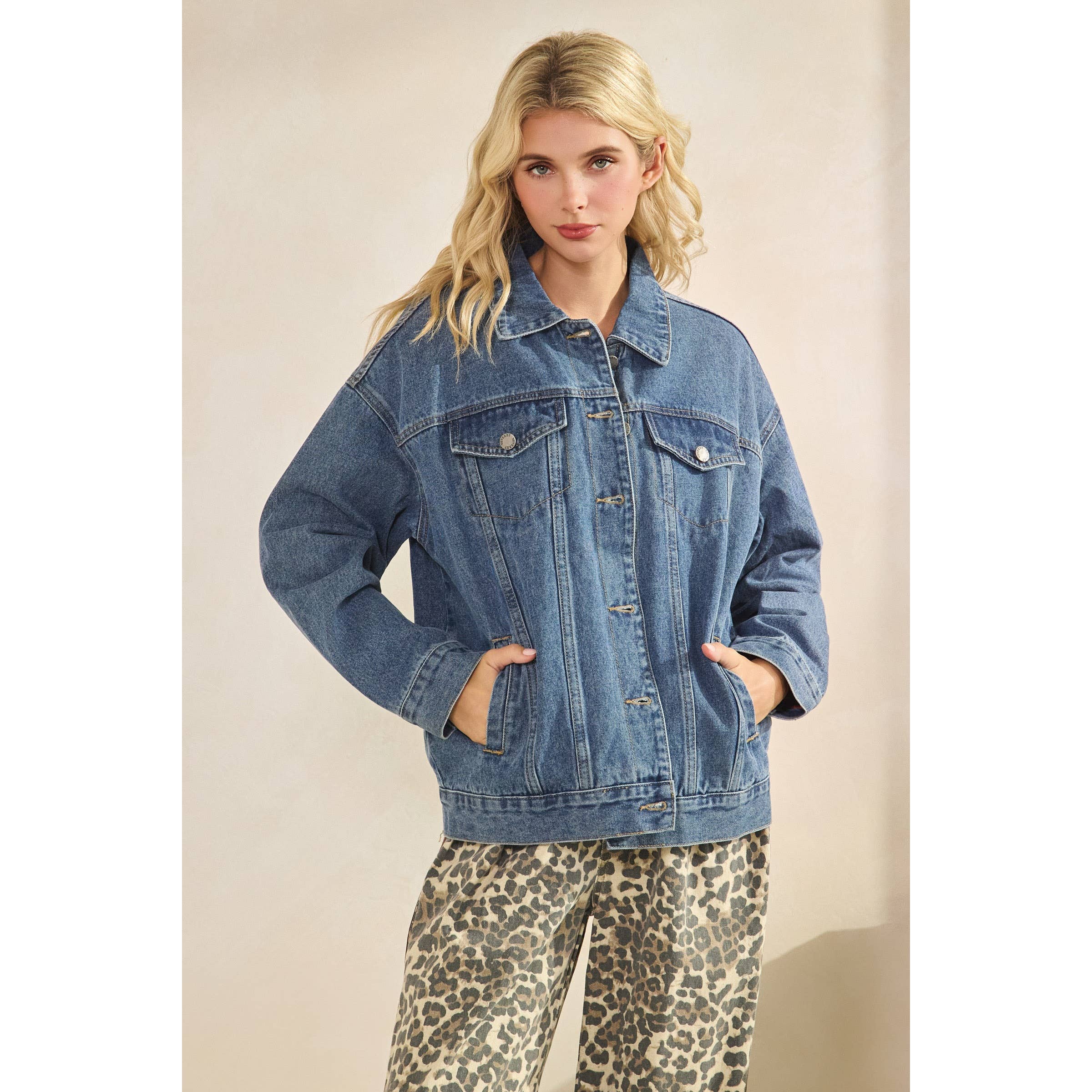 Woman wearing a blue denim jacket and leopard print pants on a beige background