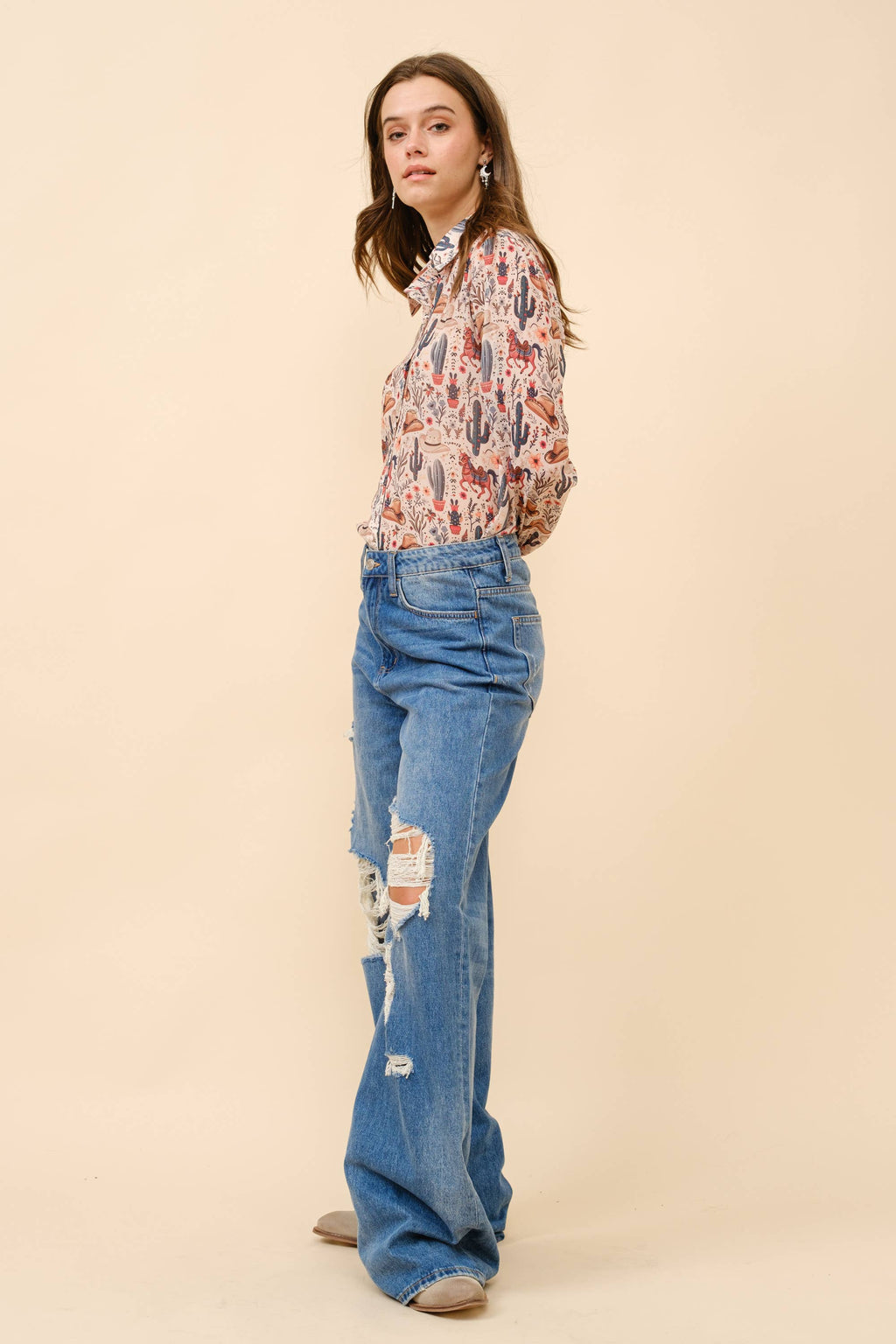 Woman wearing a floral blouse and blue jeans on a beige background