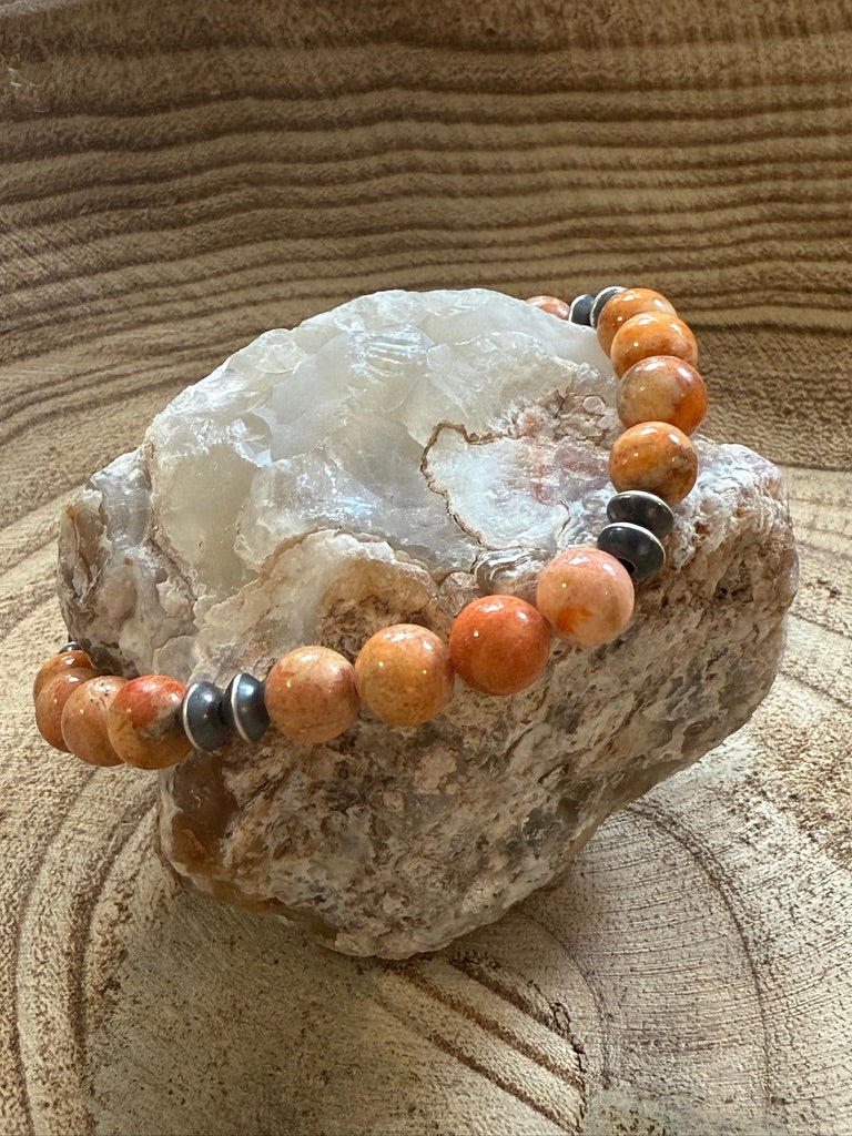 Bracelet with orange and black beads on a rock with a natural stone background