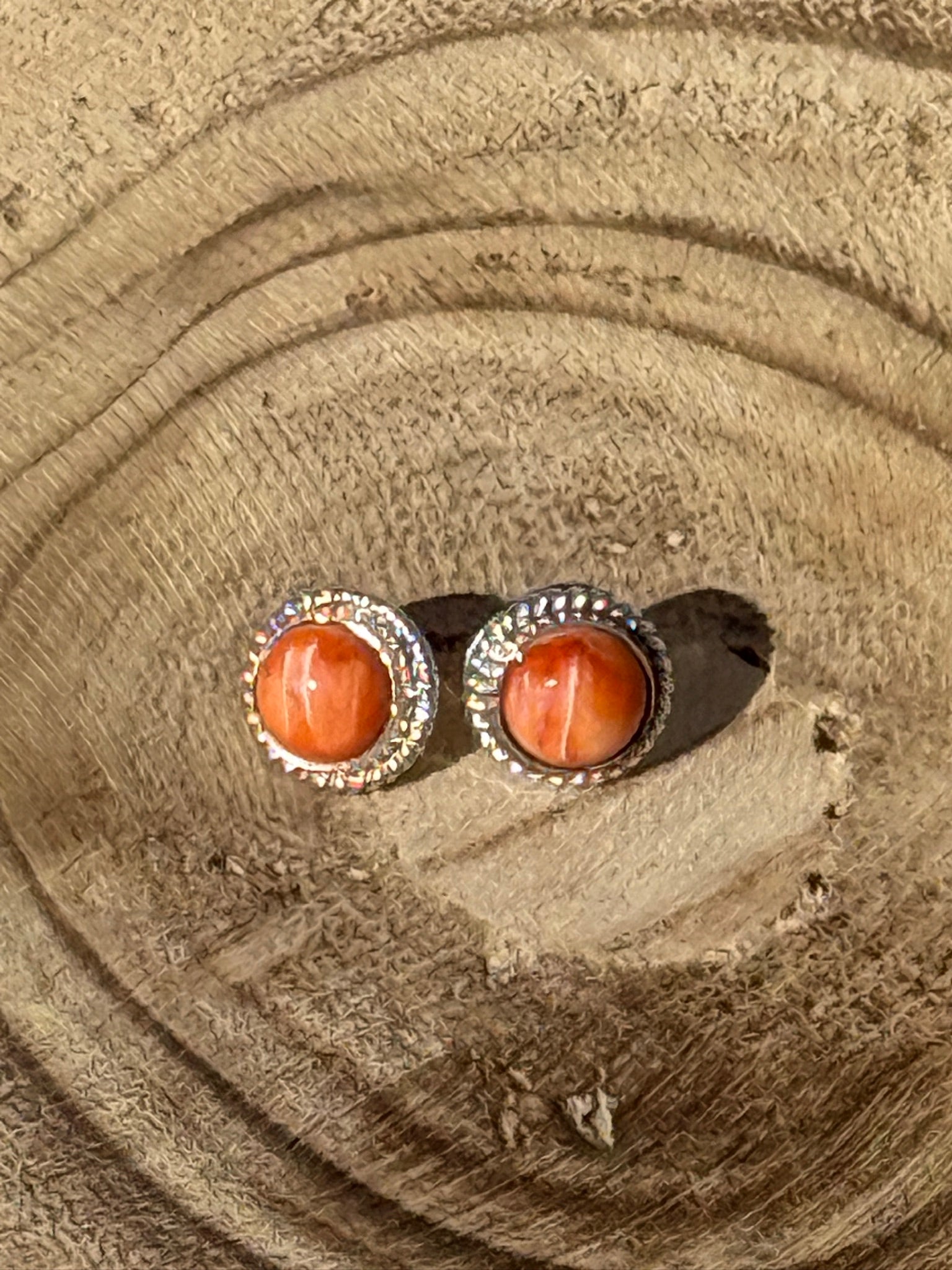 Pair of earrings with orange stones on a wooden surface