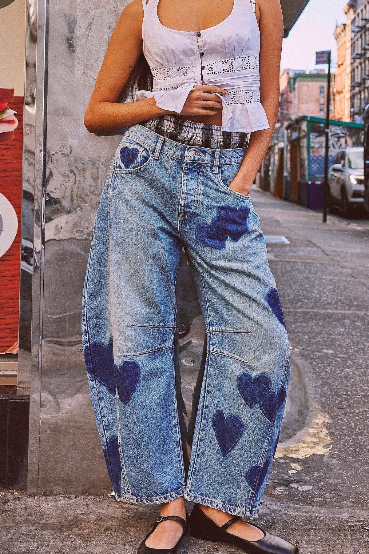 Person wearing blue jeans with heart patterns on a city street.