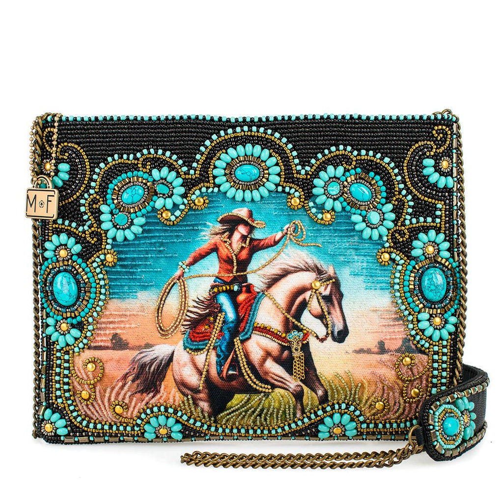 Decorative clutch with a cowboy on horseback design and turquoise embellishments.
