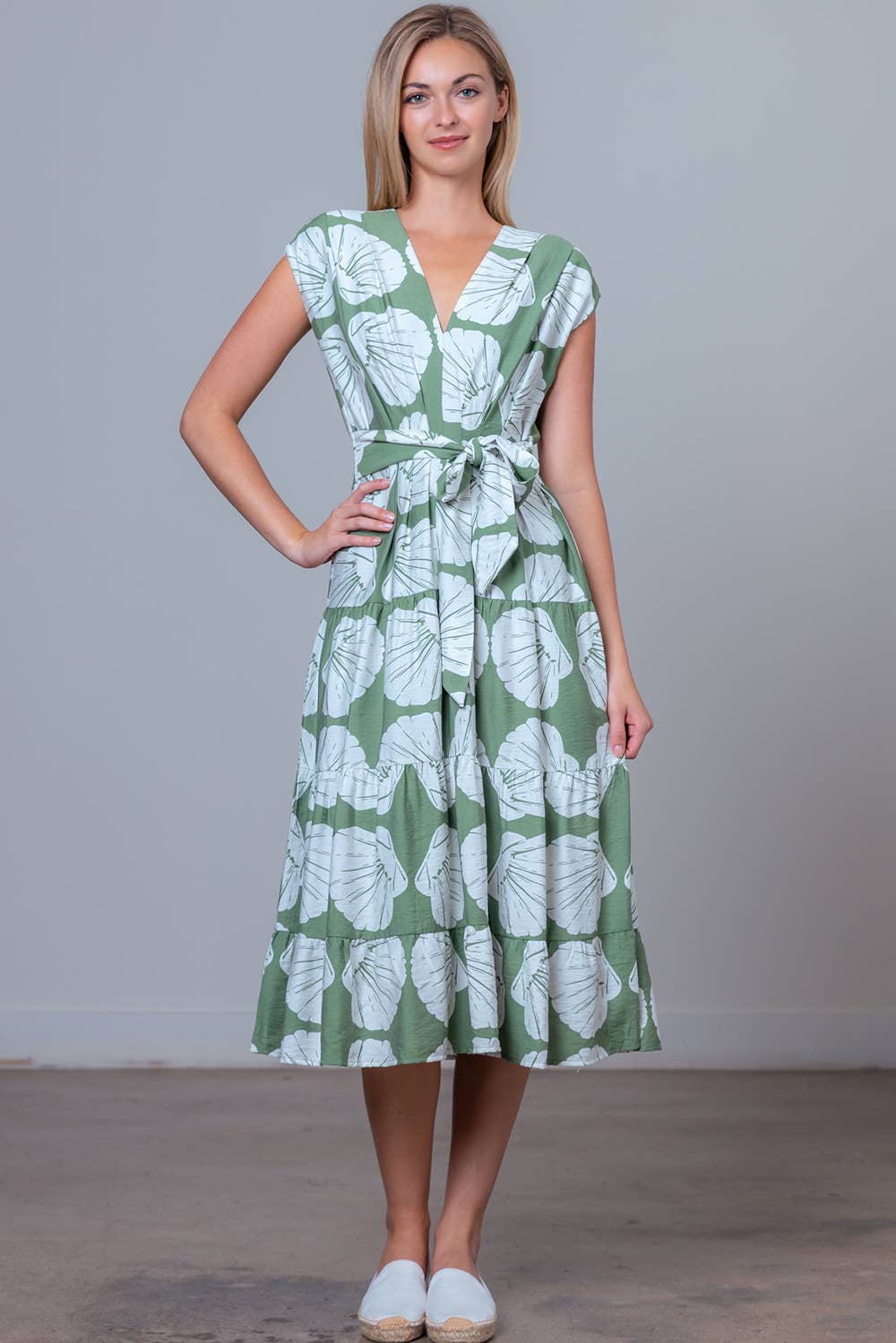Woman wearing a green and white leaf-patterned dress against a plain background
