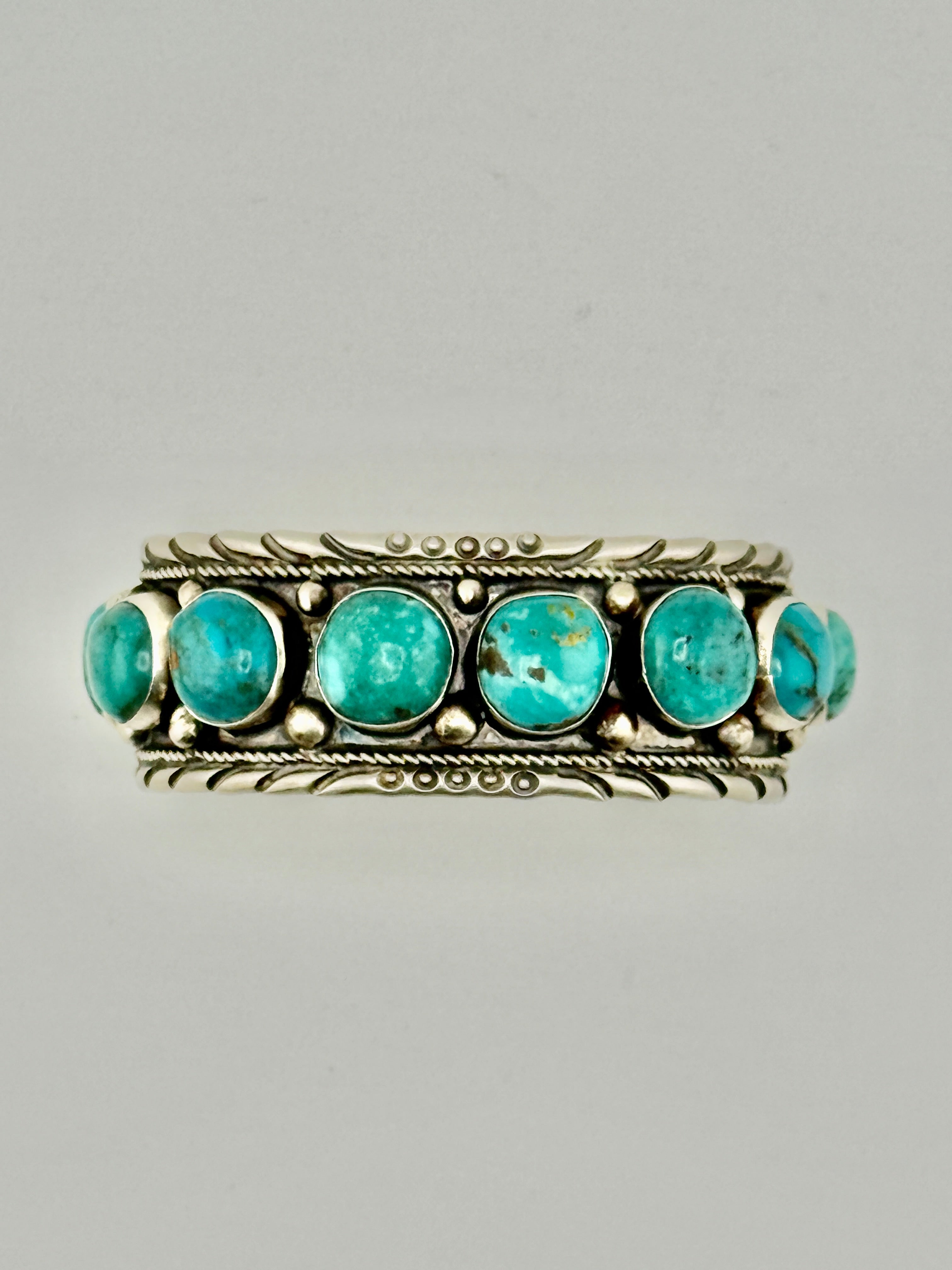 Ring with turquoise stones and silver band on a gray background