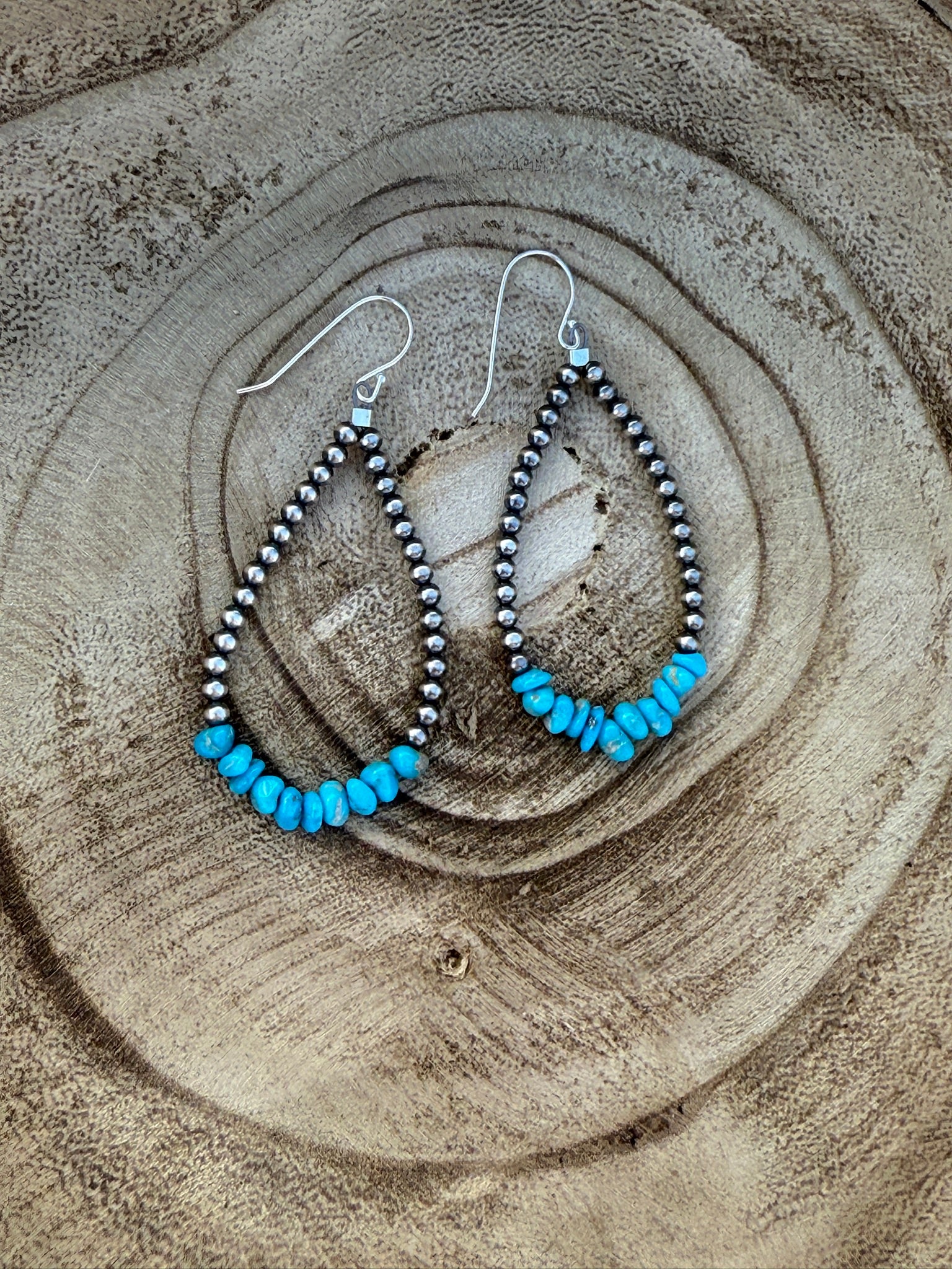 Pair of beaded earrings with blue beads on a wooden surface