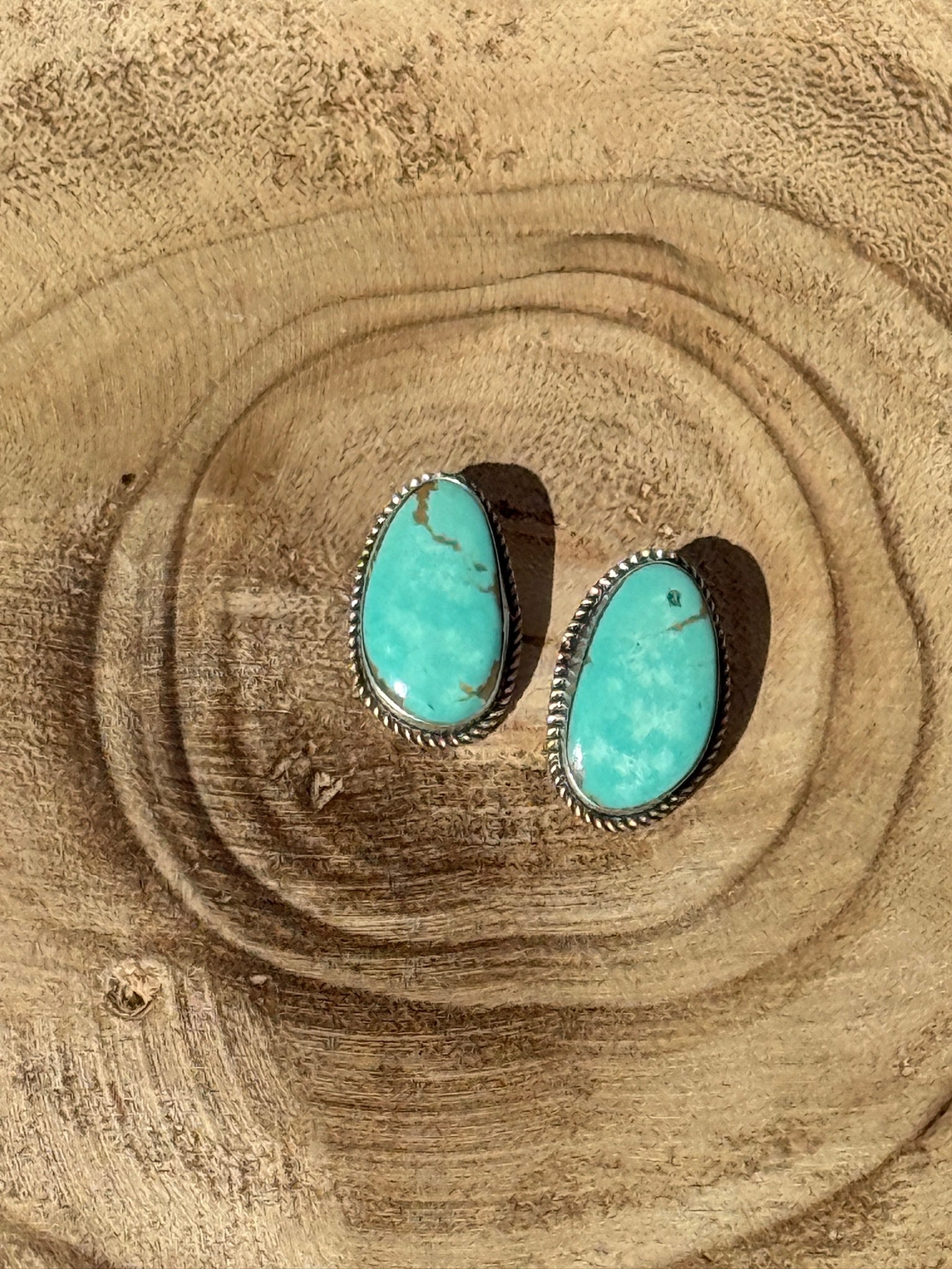 Turquoise stone earrings on a wooden surface