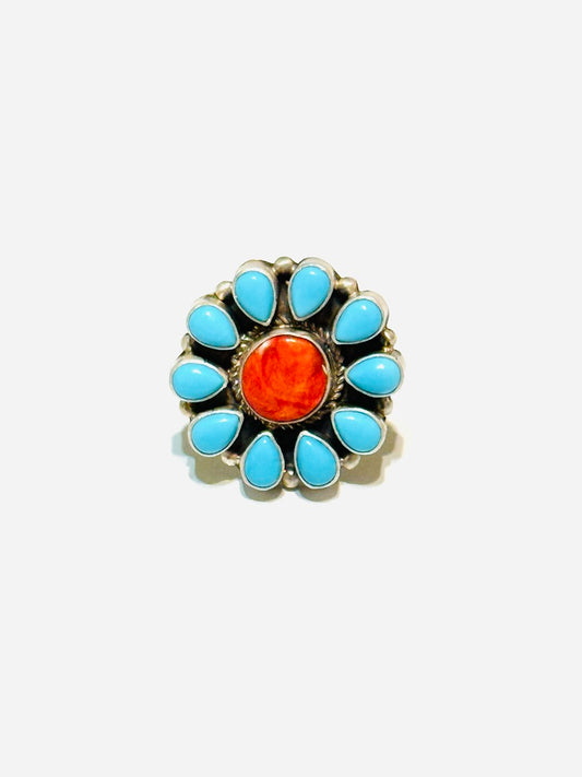 Jewelry item with turquoise stones and an orange center on a white background