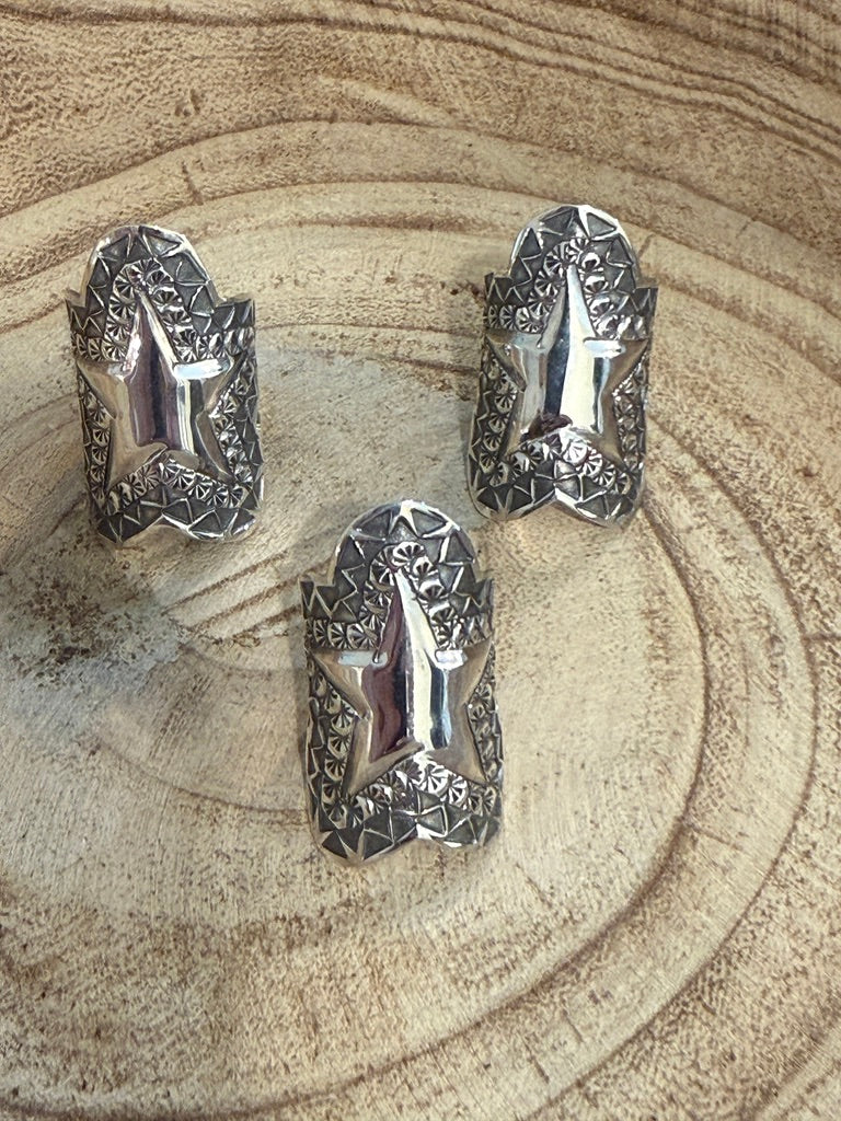 Three silver rings with intricate designs on a textured surface