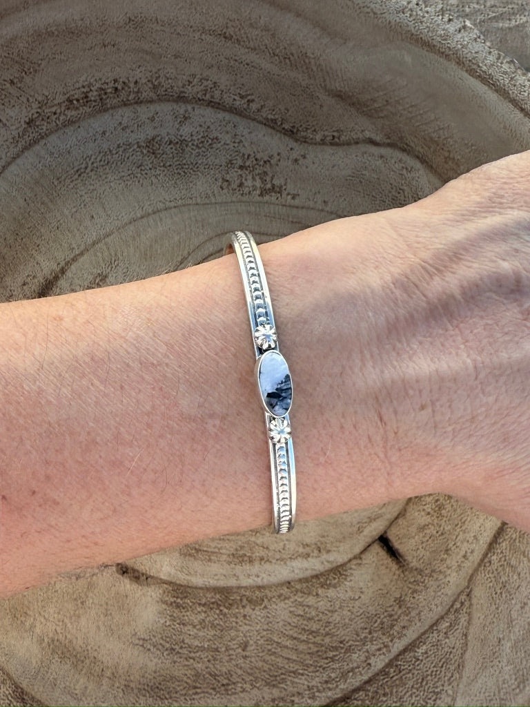 Silver bracelet on a wrist with a sandy background