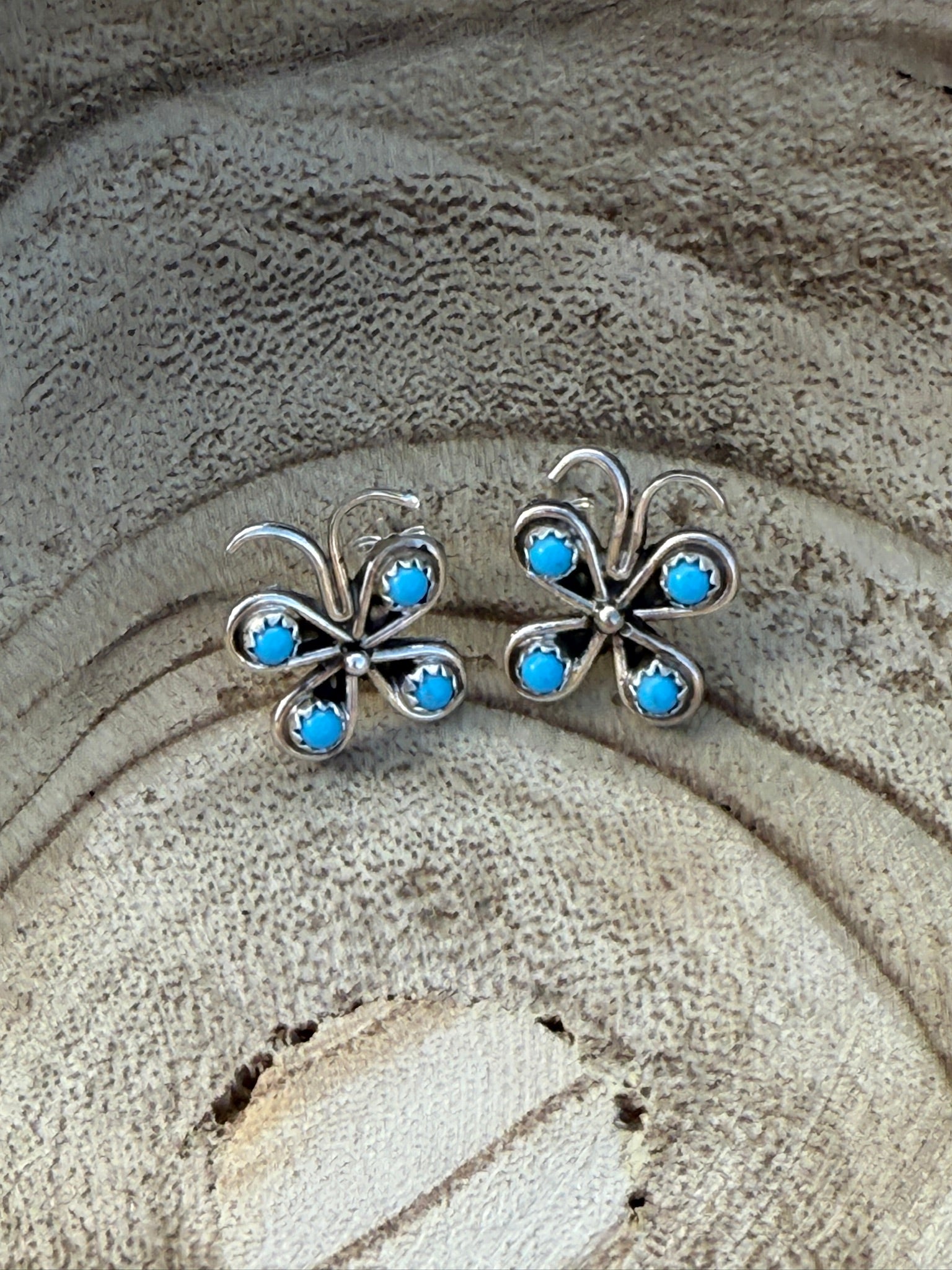 Butterfly-shaped earrings with blue stones on a textured surface