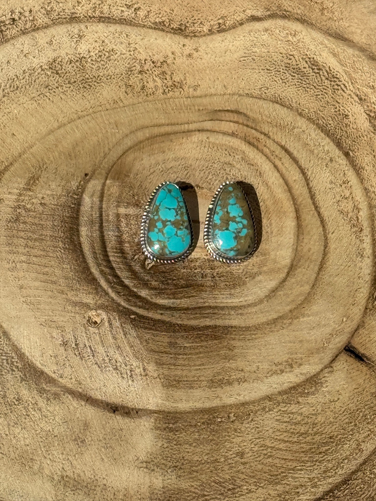 Turquoise stone earrings on a wooden surface