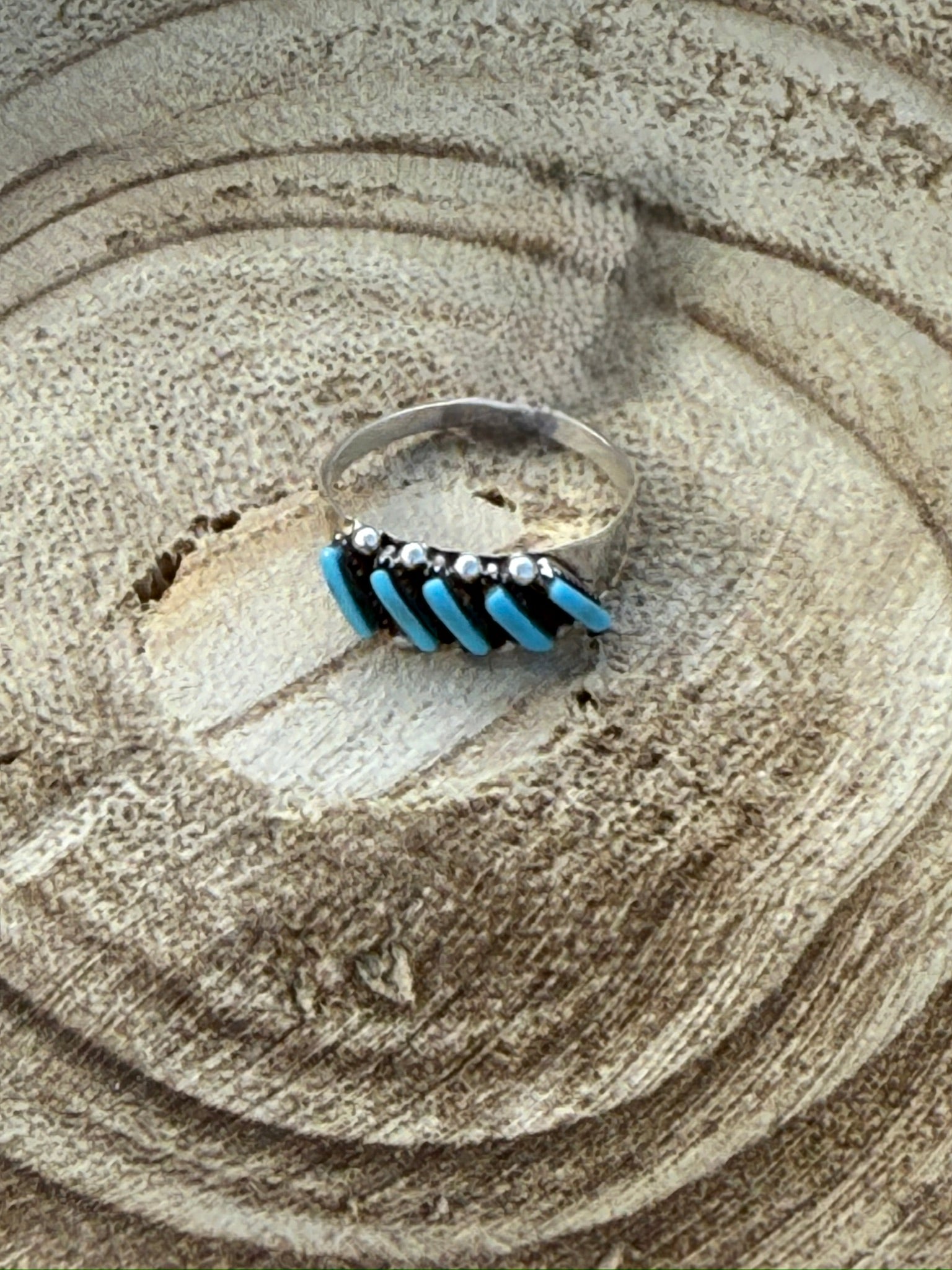 Silver ring with blue and black accents on a textured surface