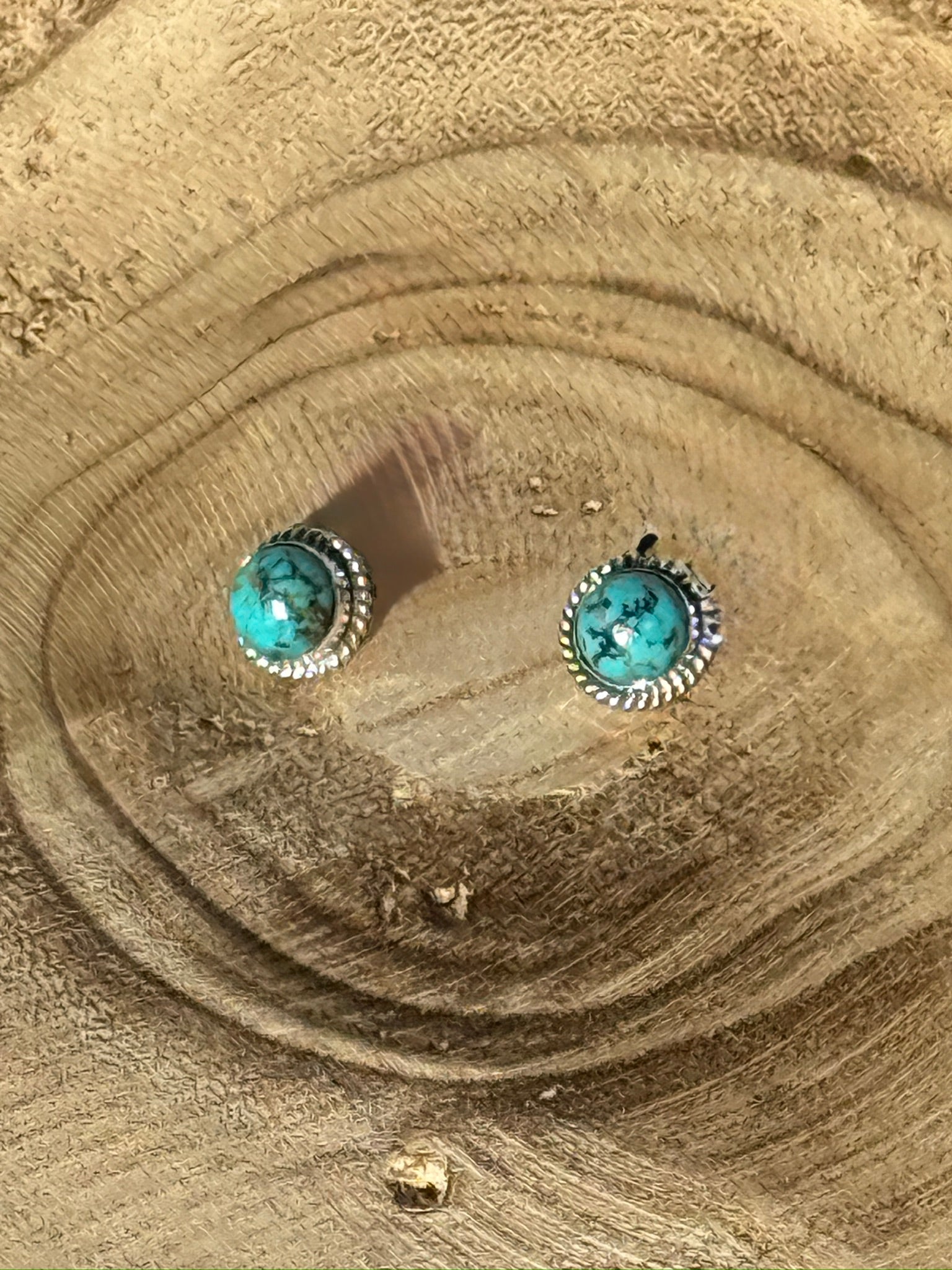 Turquoise stone earrings on a wooden surface