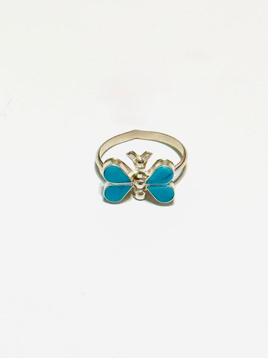 Butterfly-shaped ring with blue wings and silver body on a white background