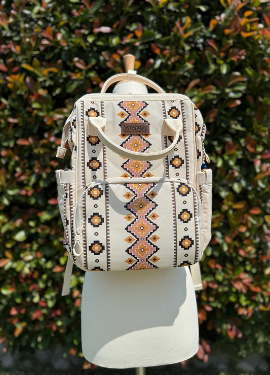 A white Wrangler Aztec printed Callie backpack displayed on a mannequin against a foliage background.