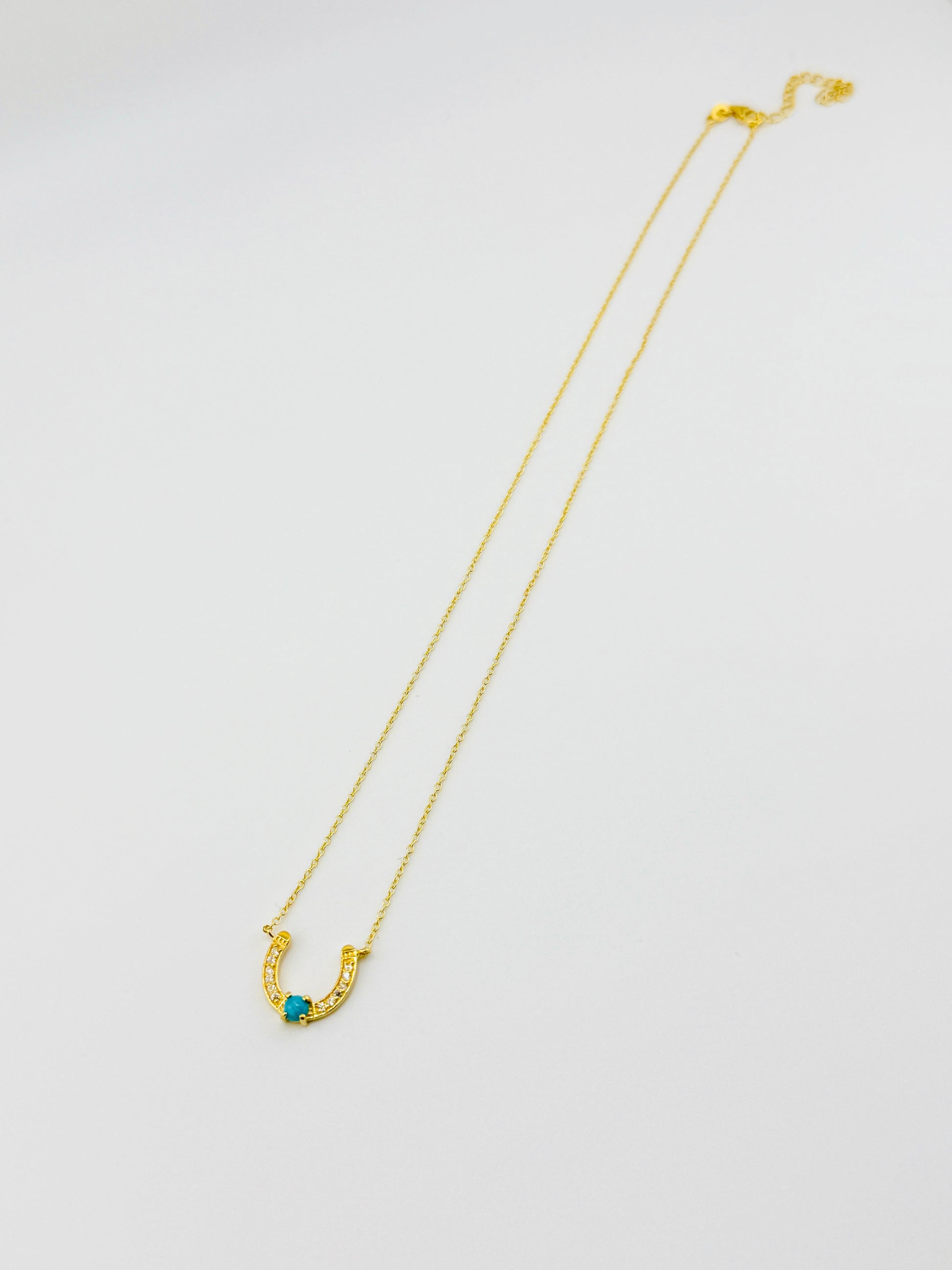 Gold necklace with a blue gemstone on a white background