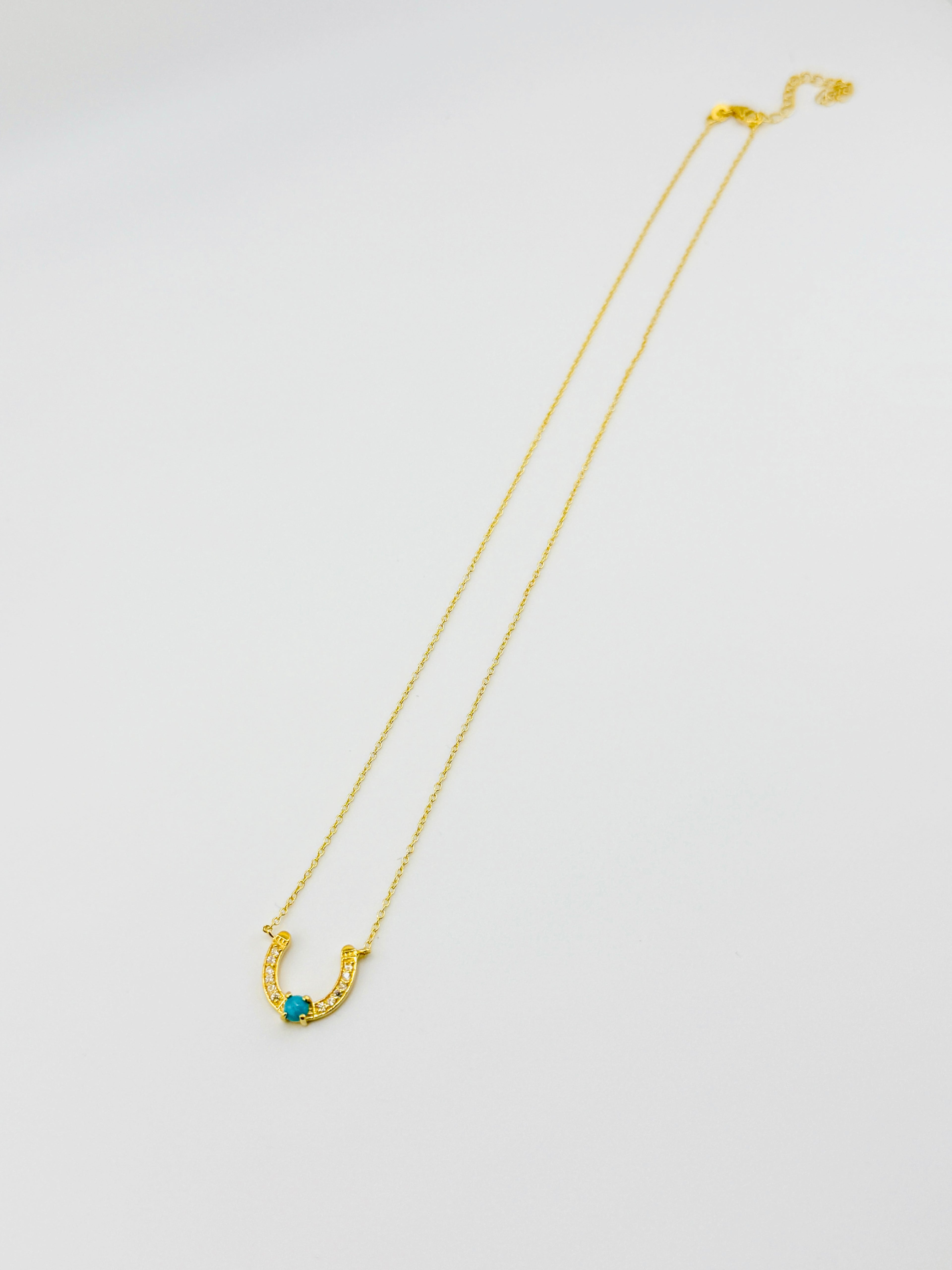 Gold necklace with a blue gemstone on a white background
