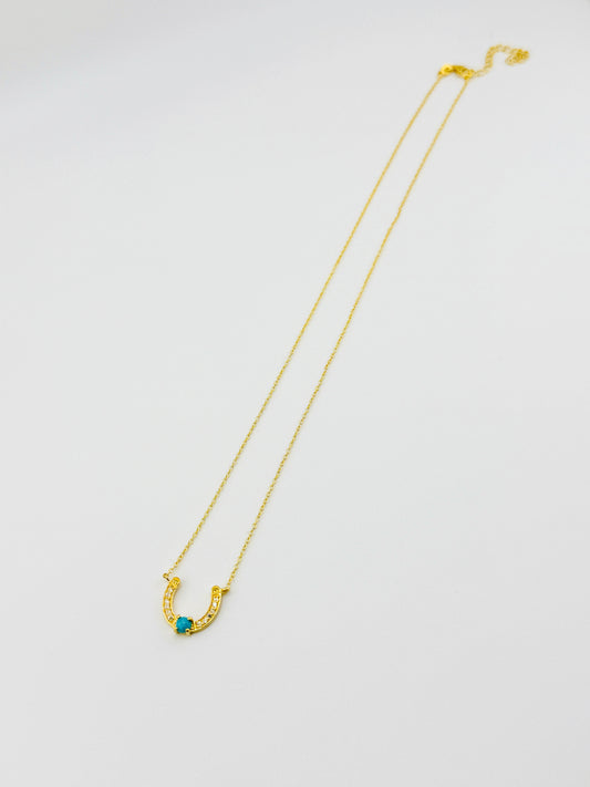 Gold necklace with a blue gemstone on a white background