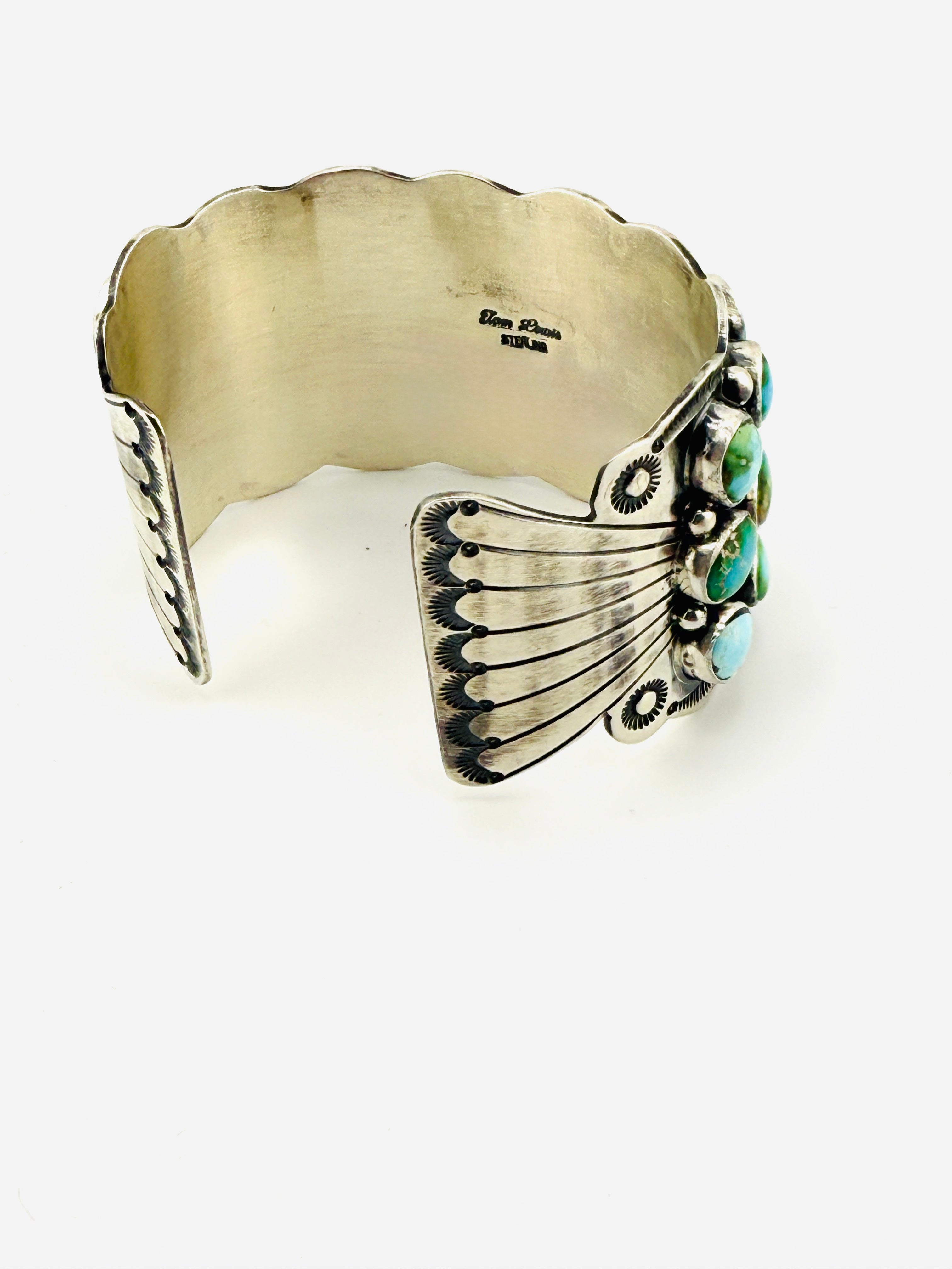 Silver cuff bracelet with turquoise stones on a white background