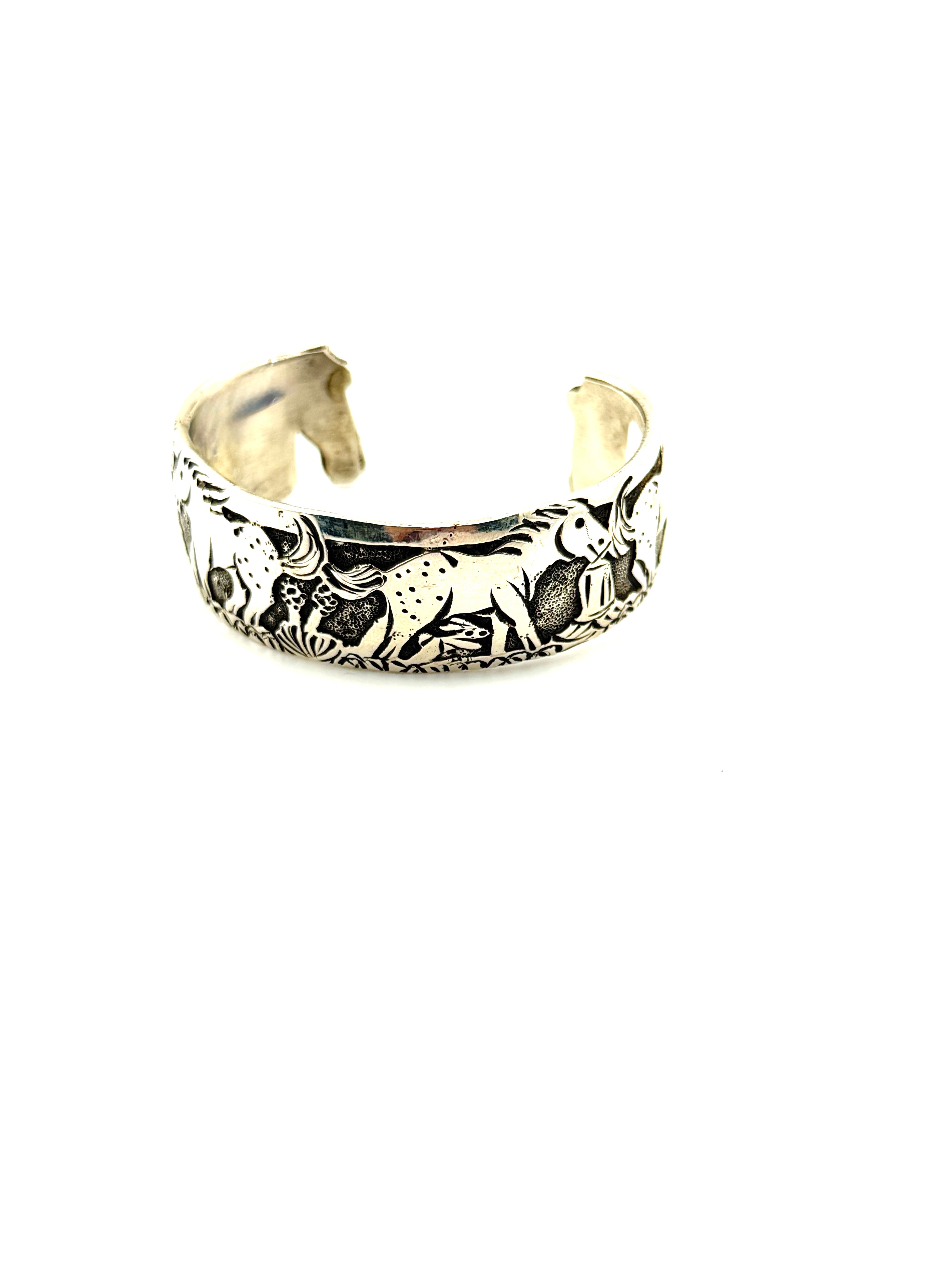 Silver cuff bracelet with engraved designs on a white background