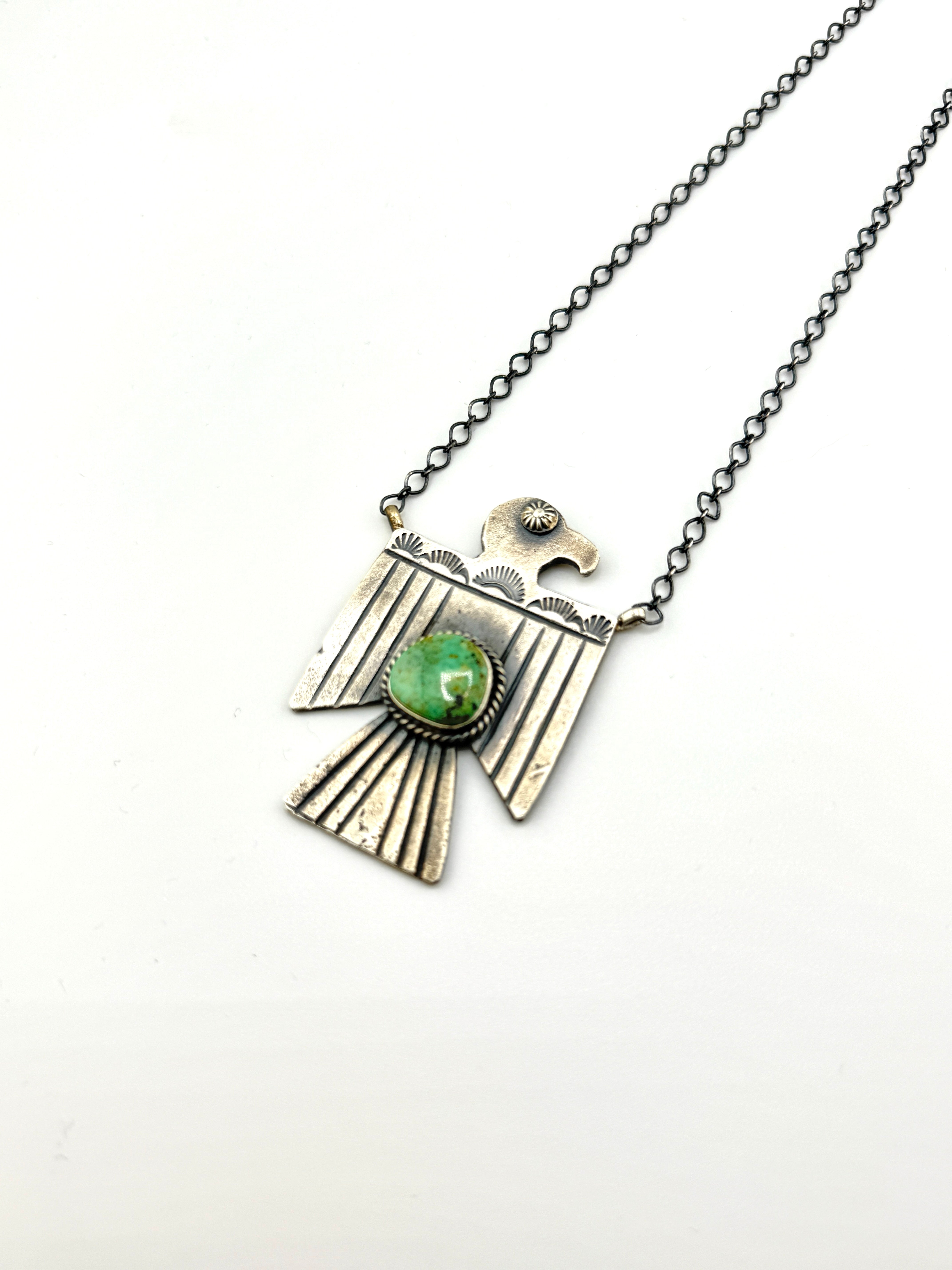 Necklace with a silver pendant featuring a green gemstone on a white background