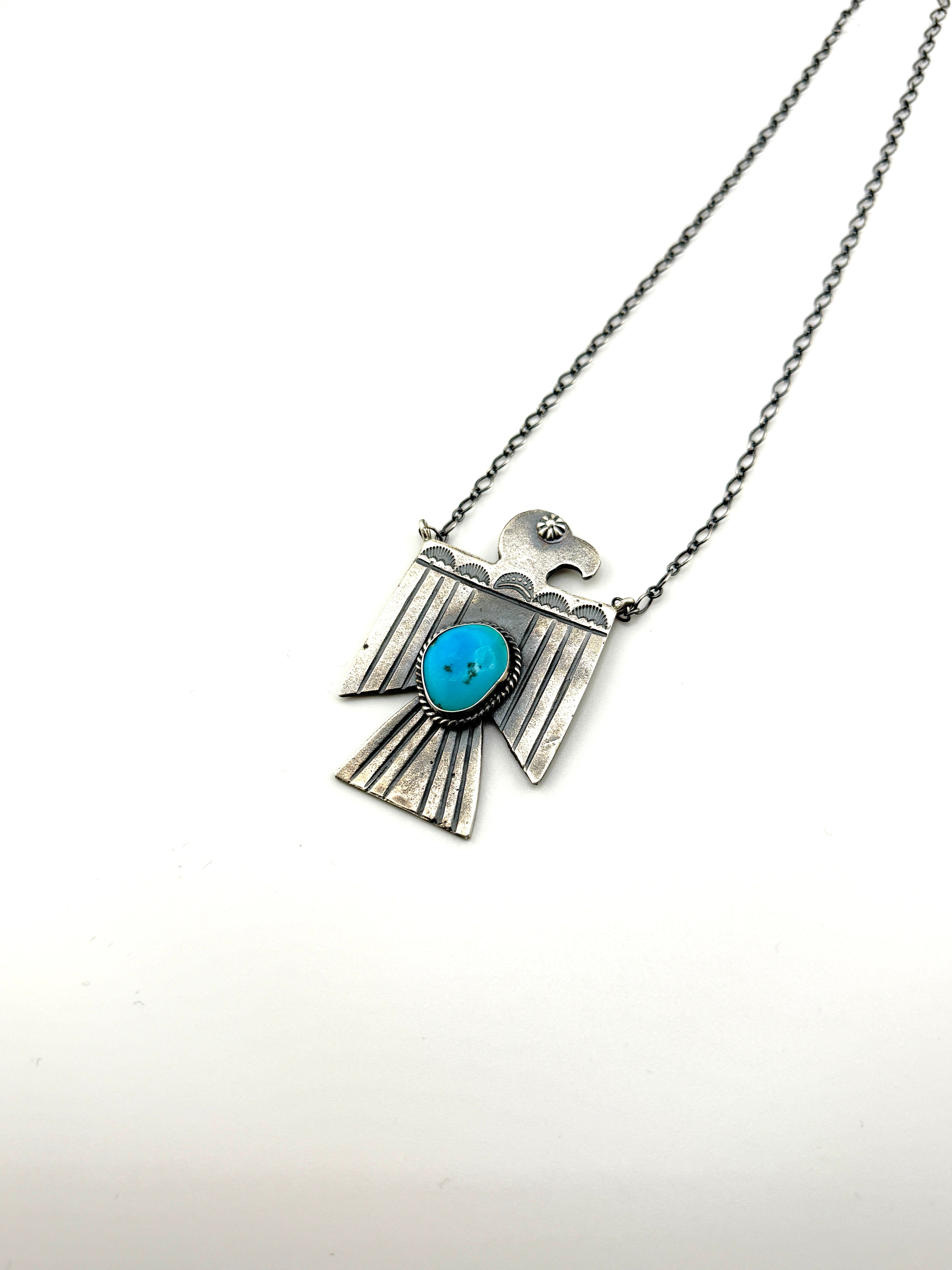 Silver necklace with a turquoise stone pendant on a white background