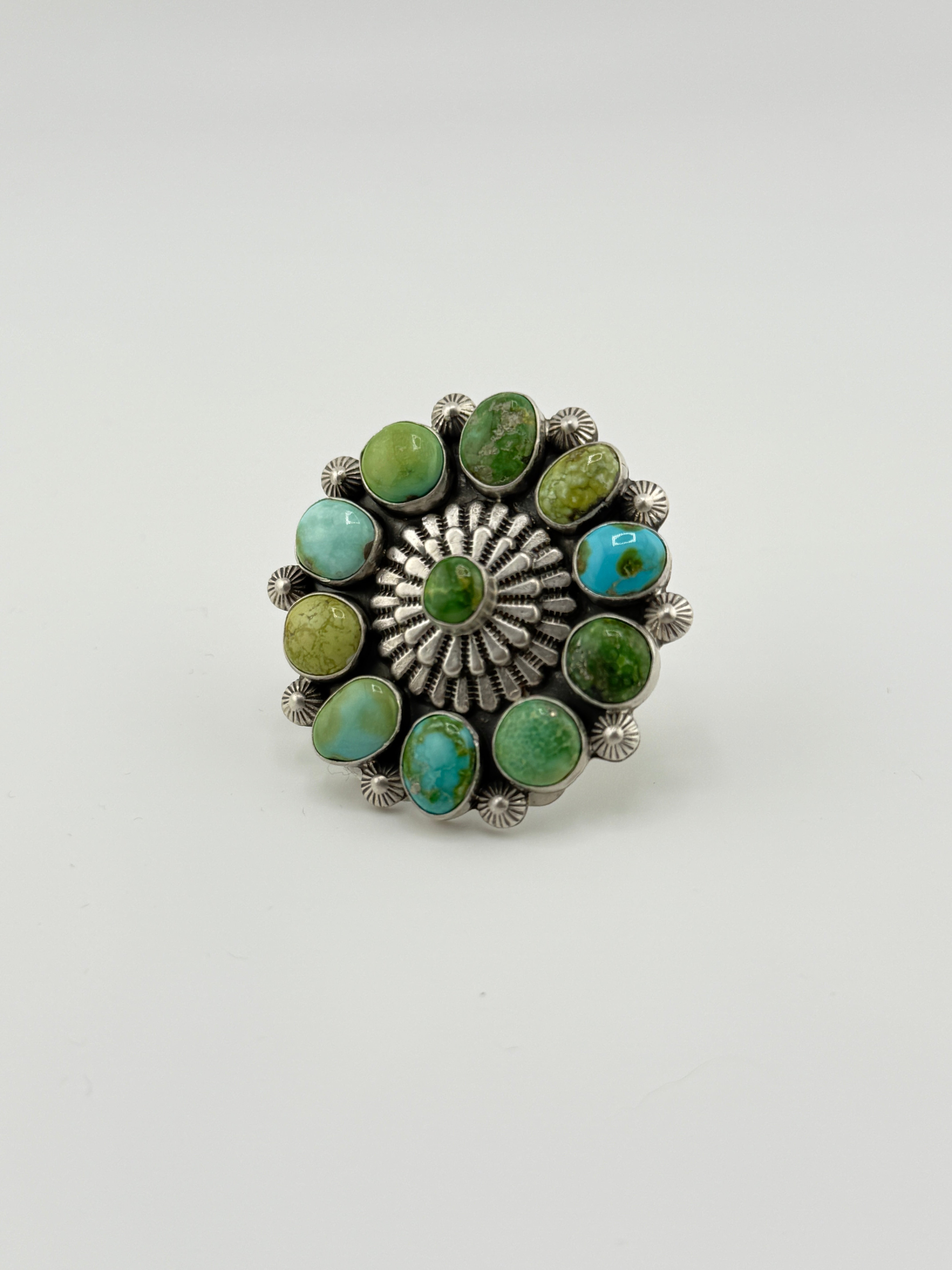 Silver ring with green and turquoise stones on a white background
