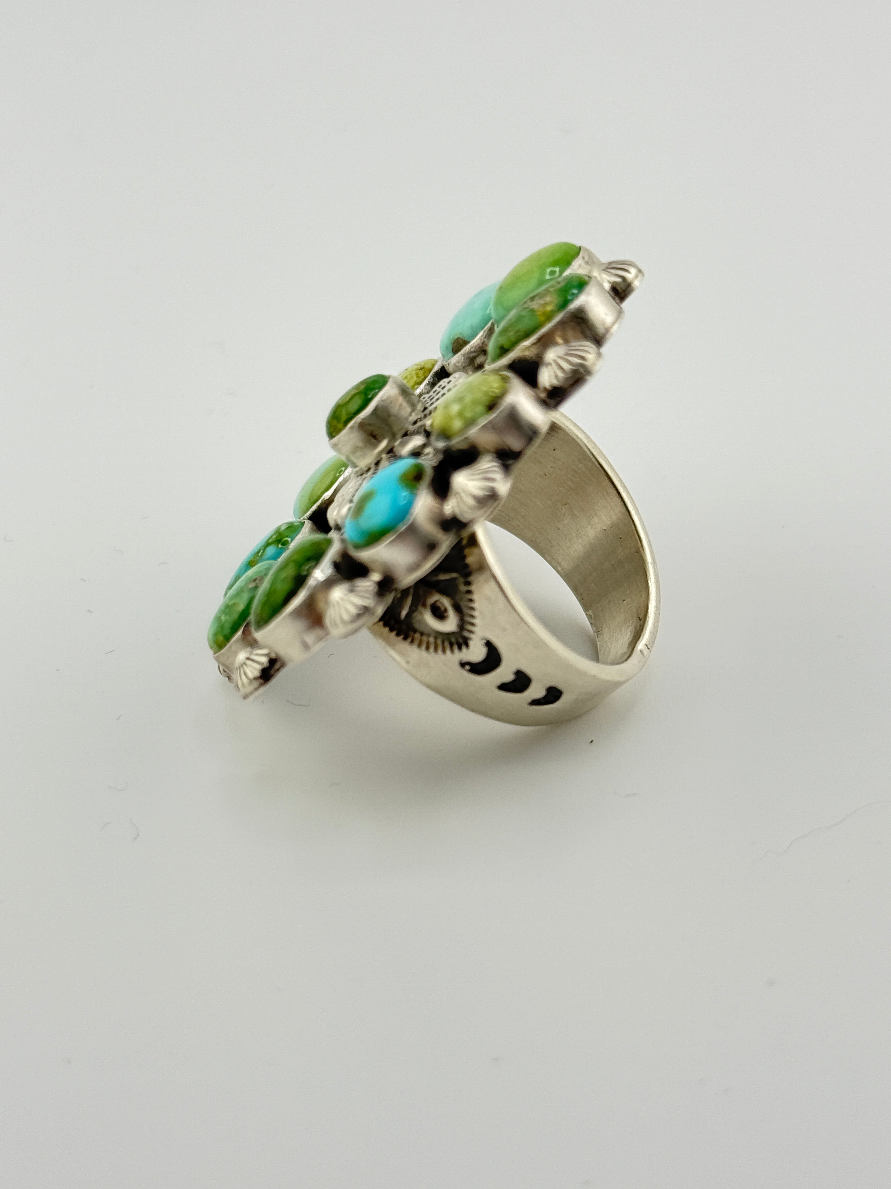 Silver ring with green and turquoise stones on a light gray background