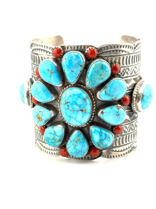 Silver bracelet with turquoise stones and red accents on a white background