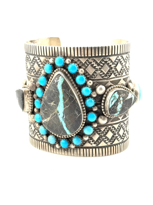 Silver cuff bracelet with turquoise stones on a white background