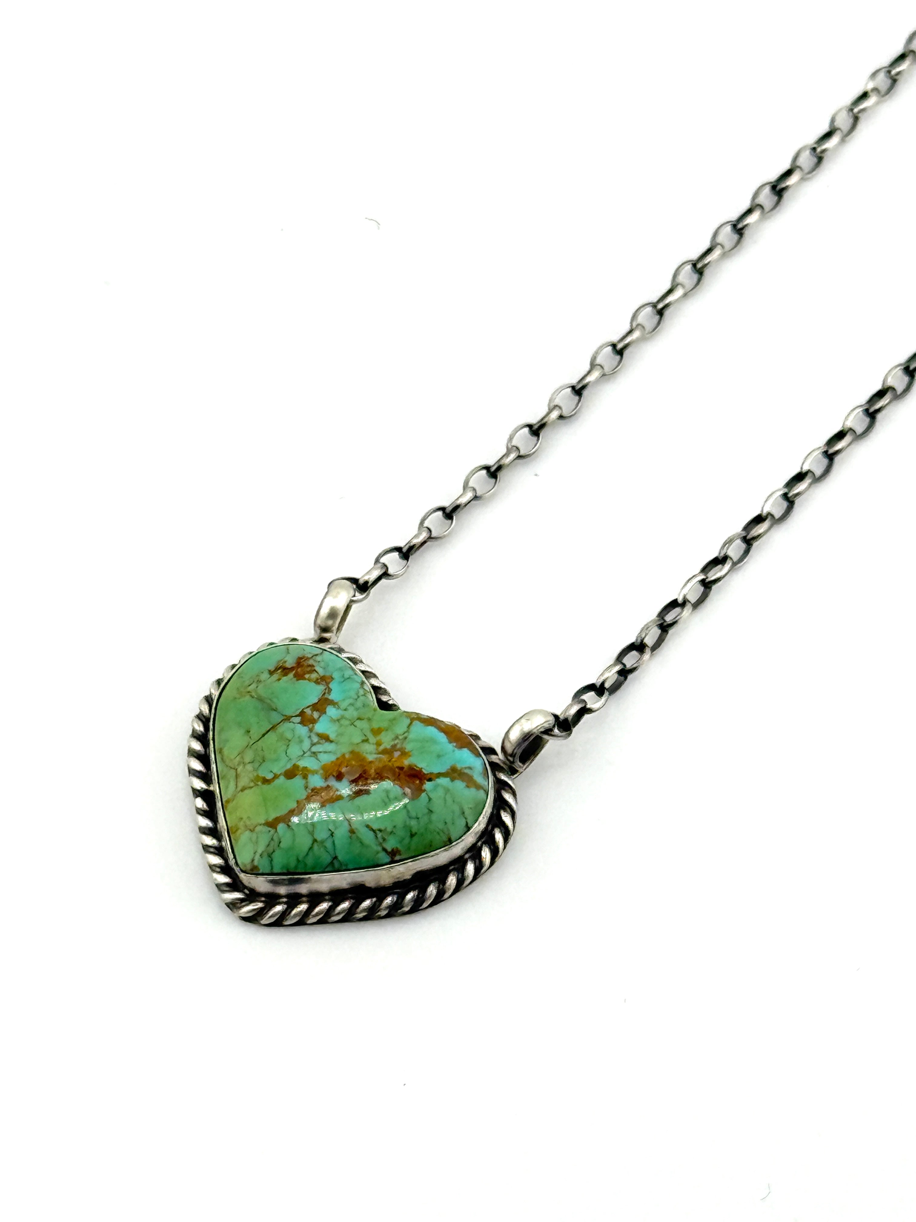 Turquoise heart-shaped pendant on a silver chain against a white background
