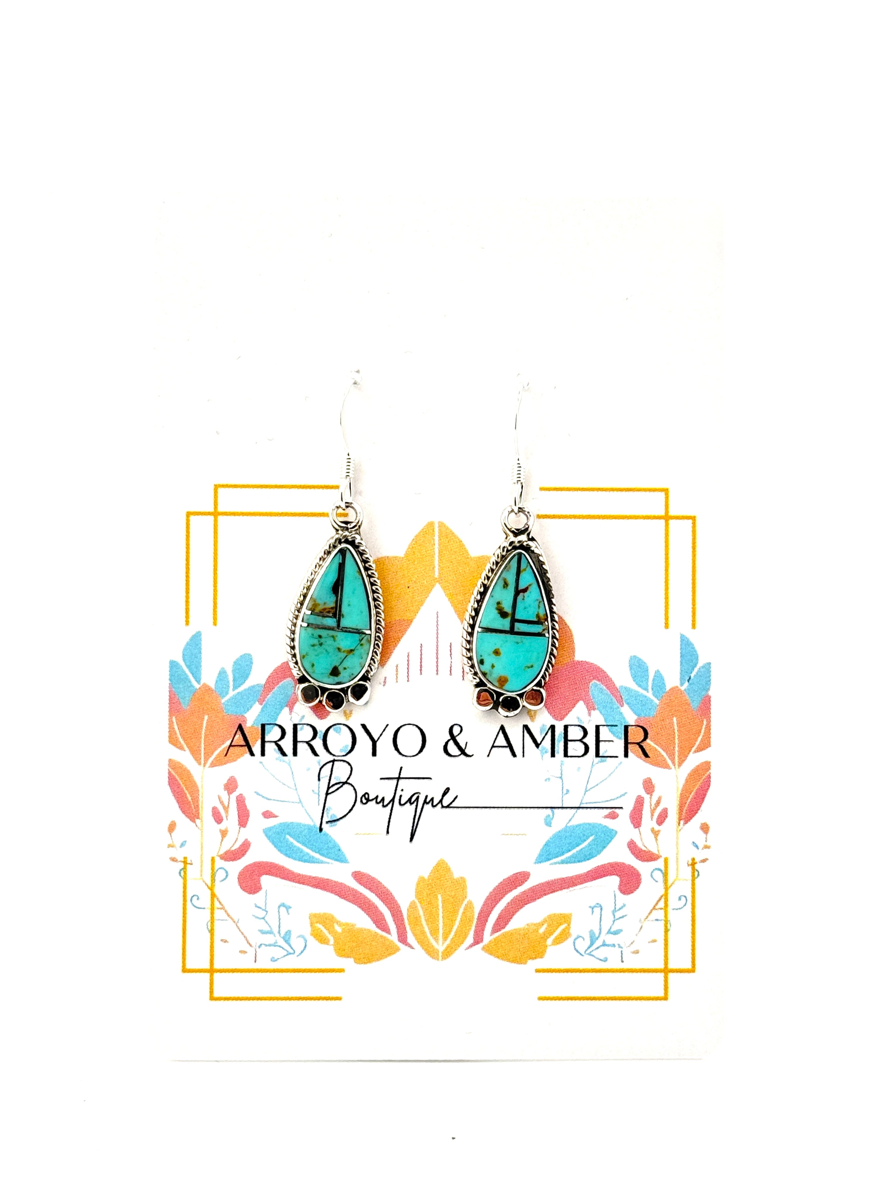 Turquoise earrings with silver hooks on a decorative card for Arroyo & Amber Boutique.