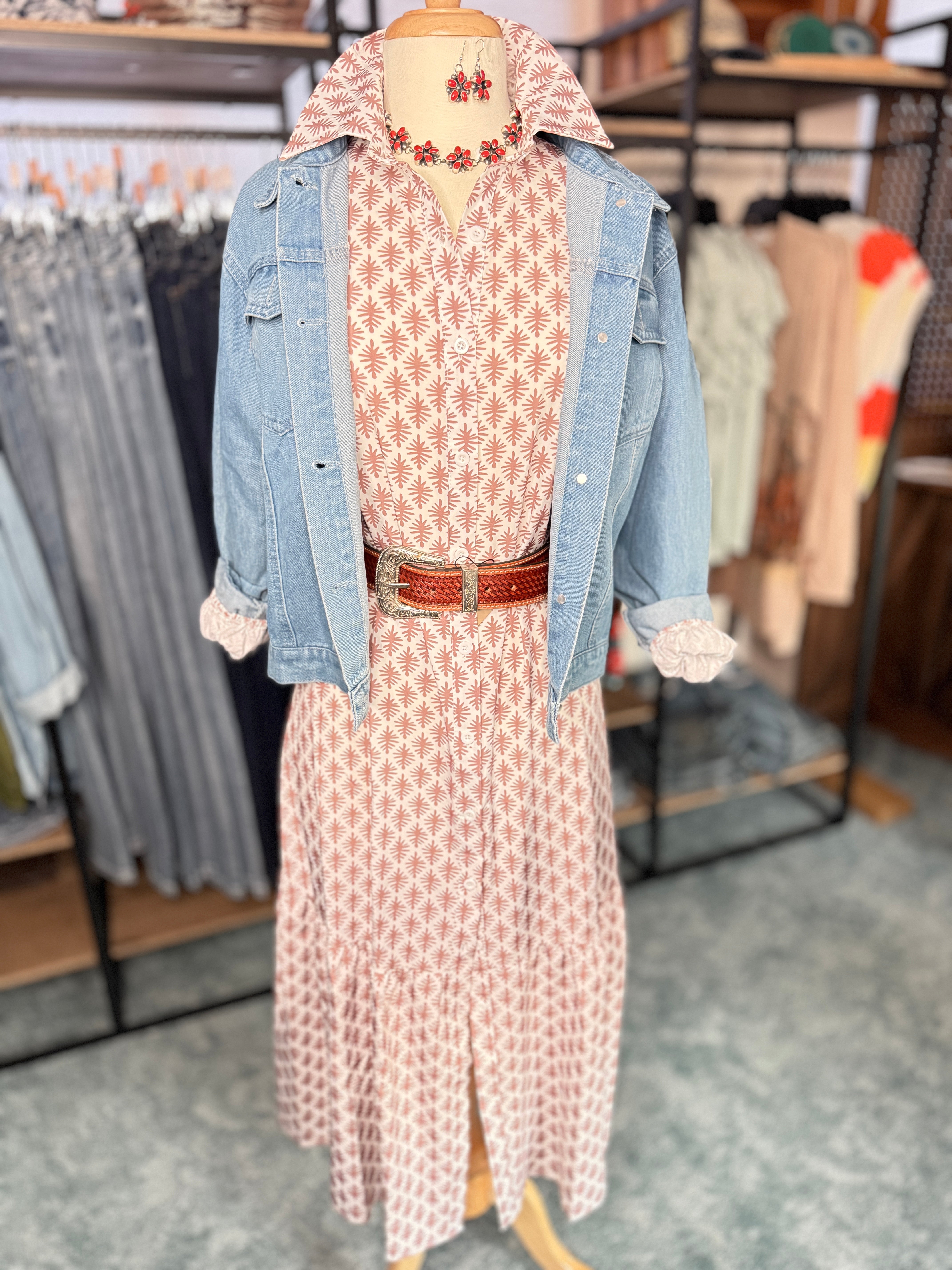 Mannequin wearing a patterned dress with a denim jacket in a store setting