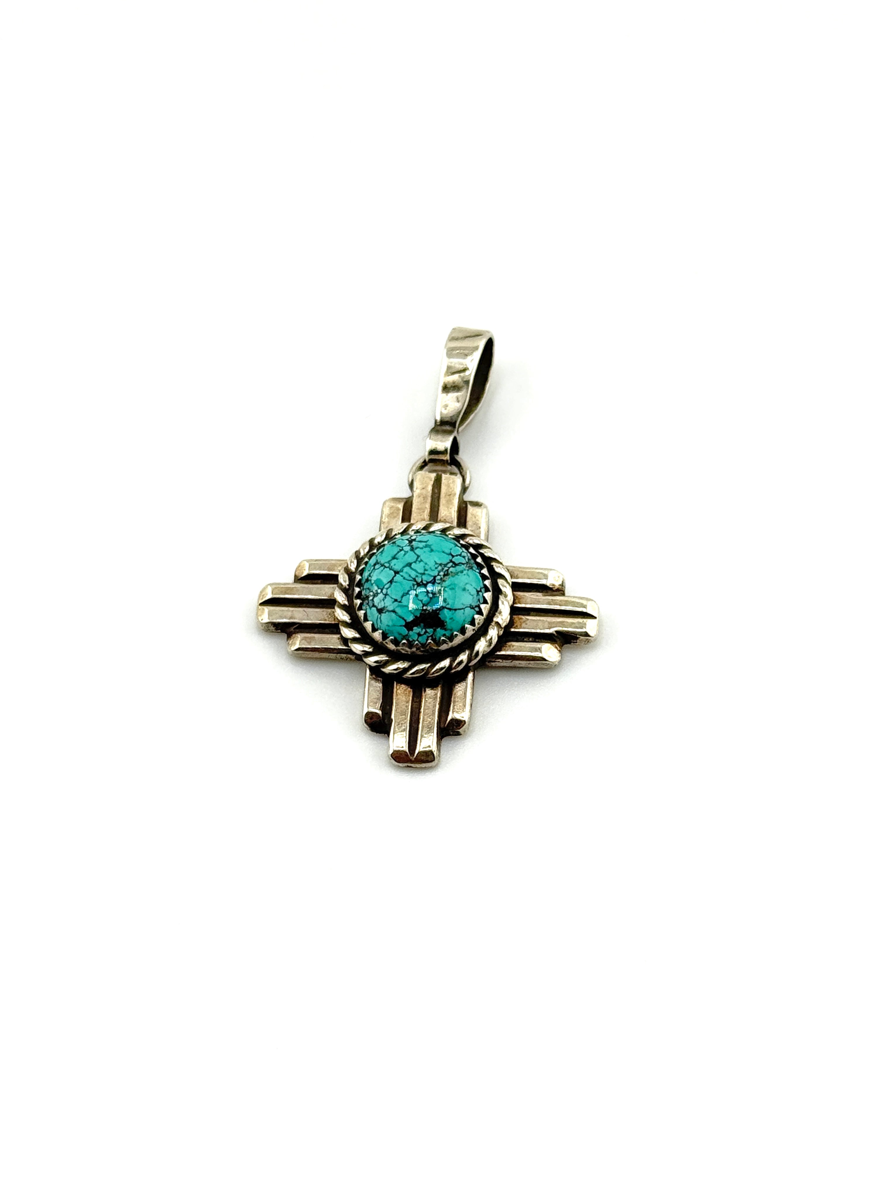 Silver cross pendant with turquoise stone on a white background