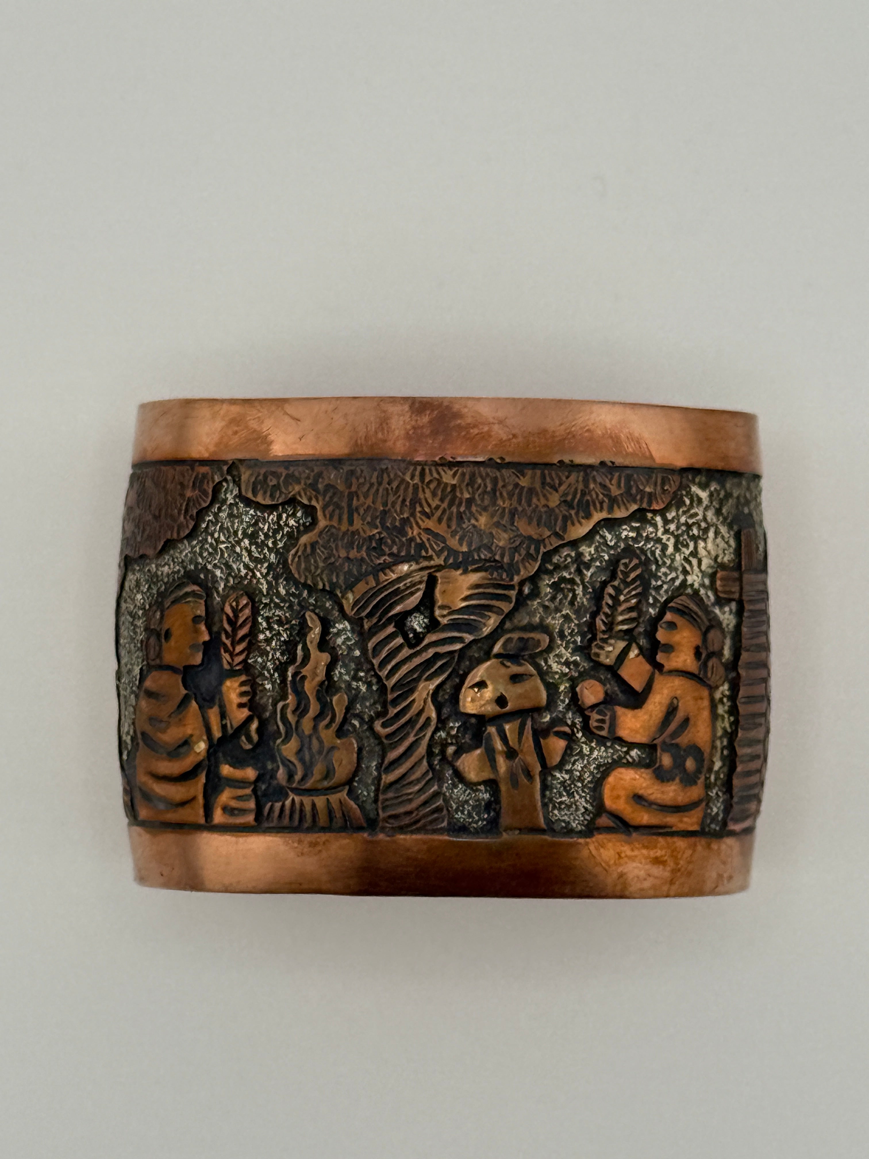 Copper ring with embossed designs on a white background