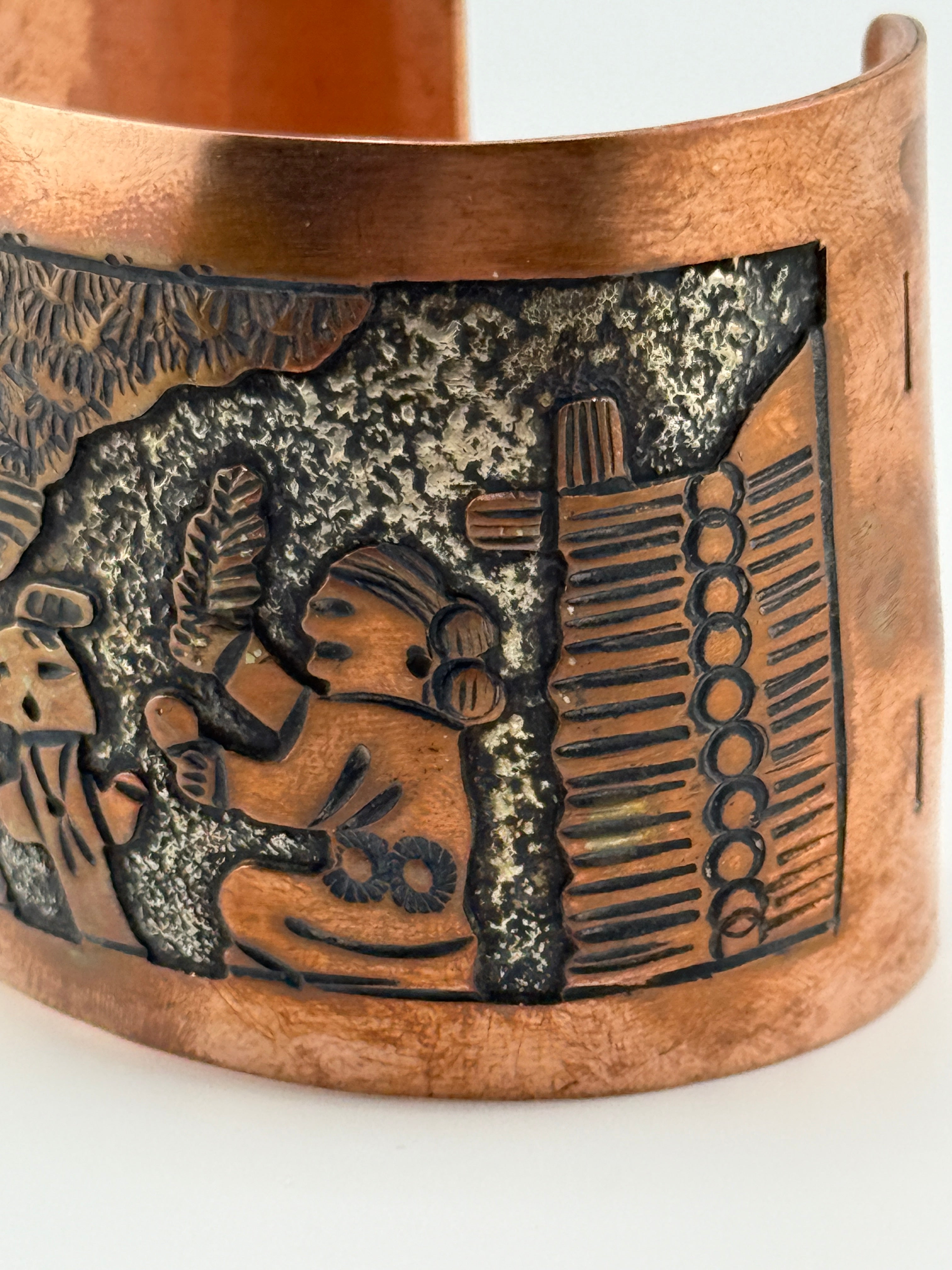 Copper bracelet with intricate embossed design on a white background