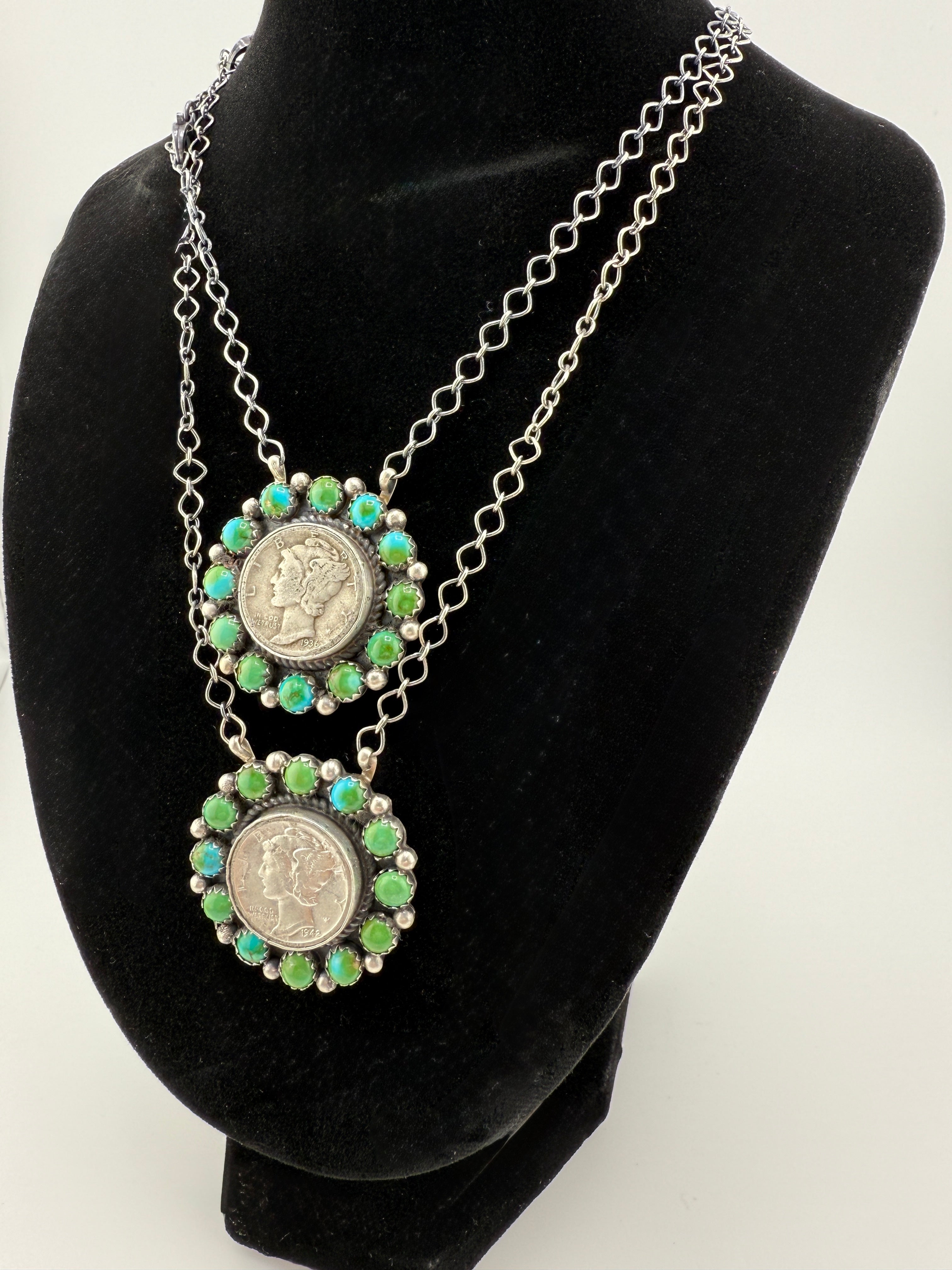 Necklace with two coin pendants on a black mannequin bust against a white background