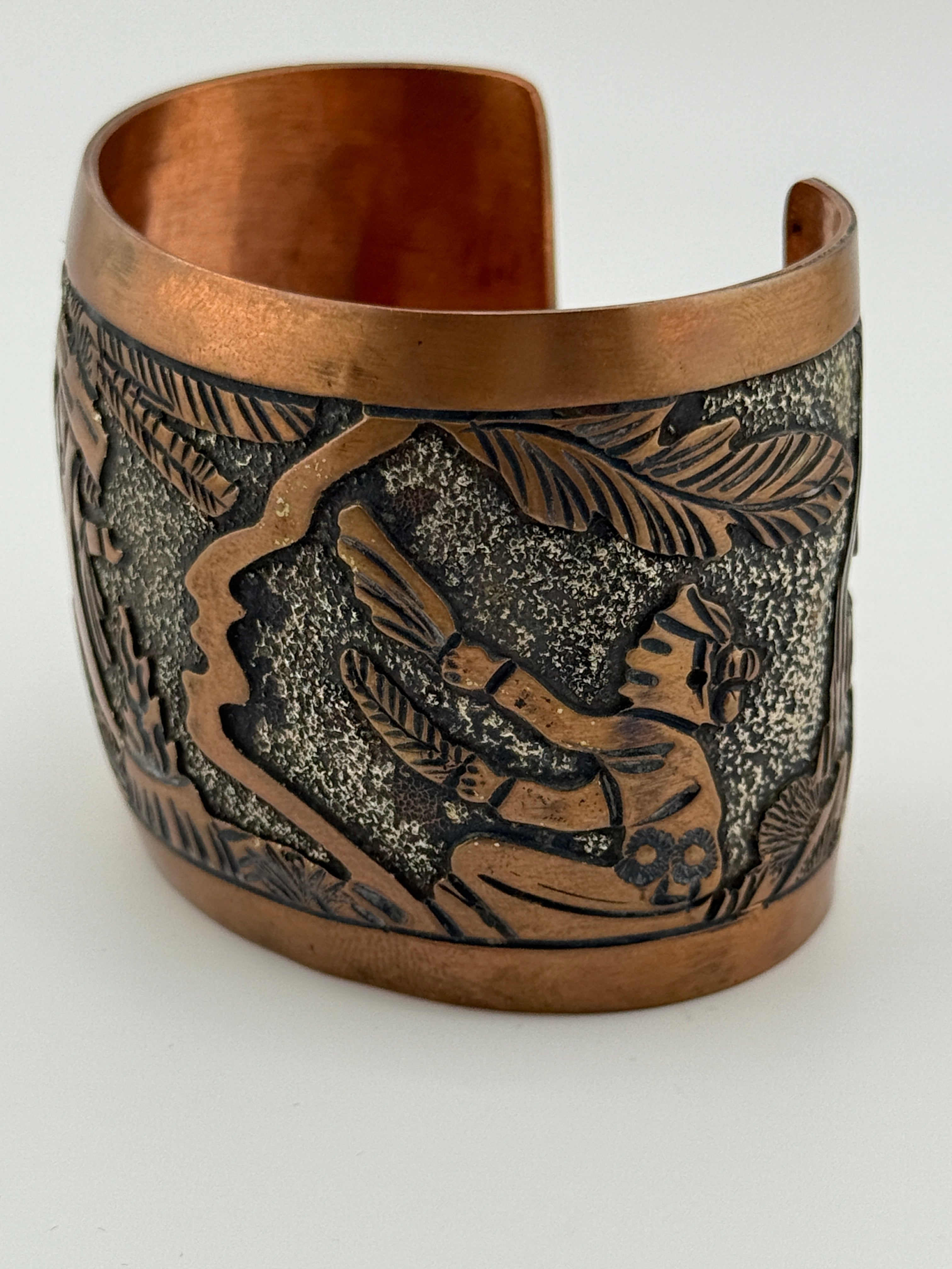 Copper cuff bracelet with embossed design on a white background
