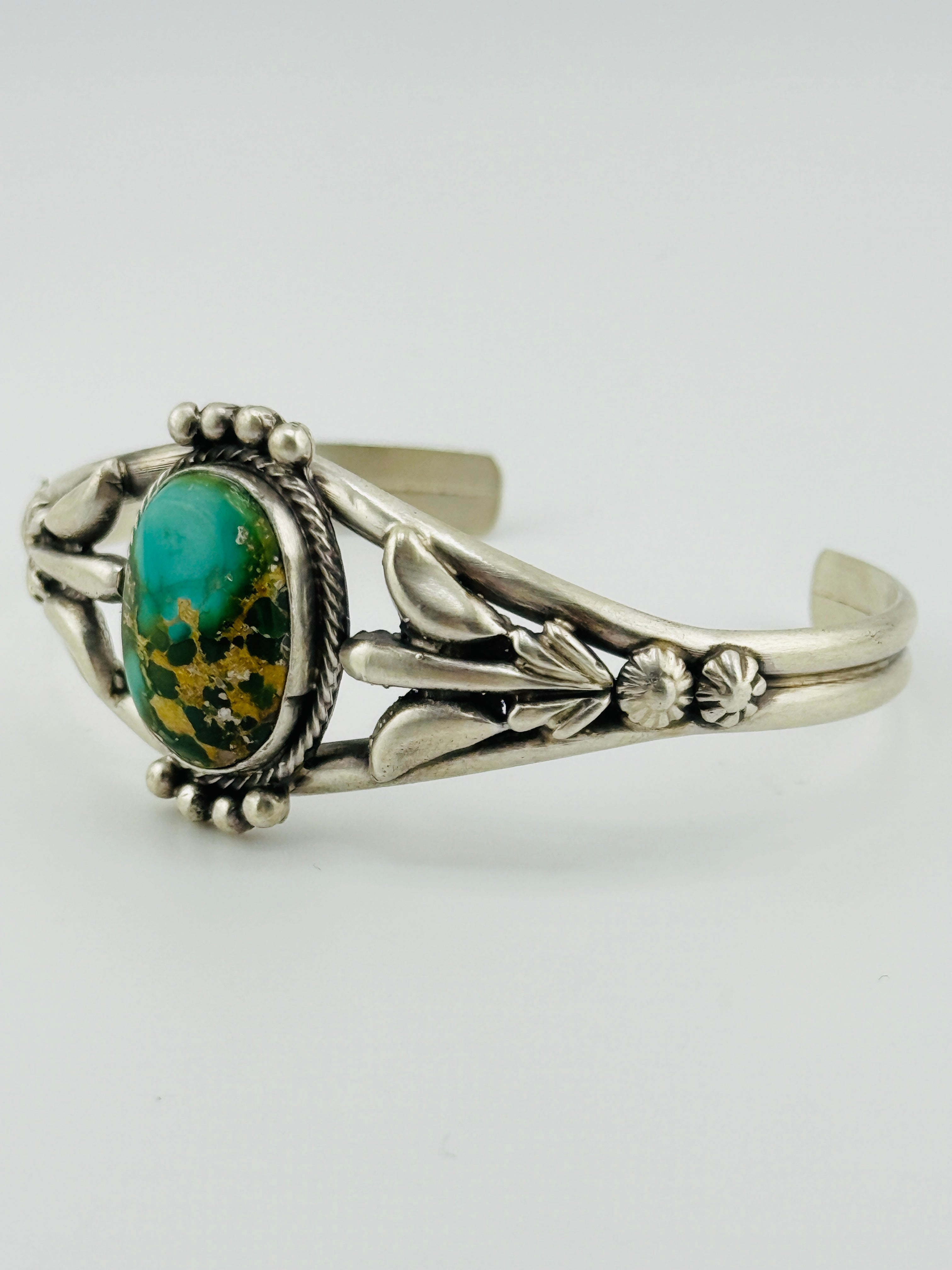 Silver bracelet with a green stone on a white background