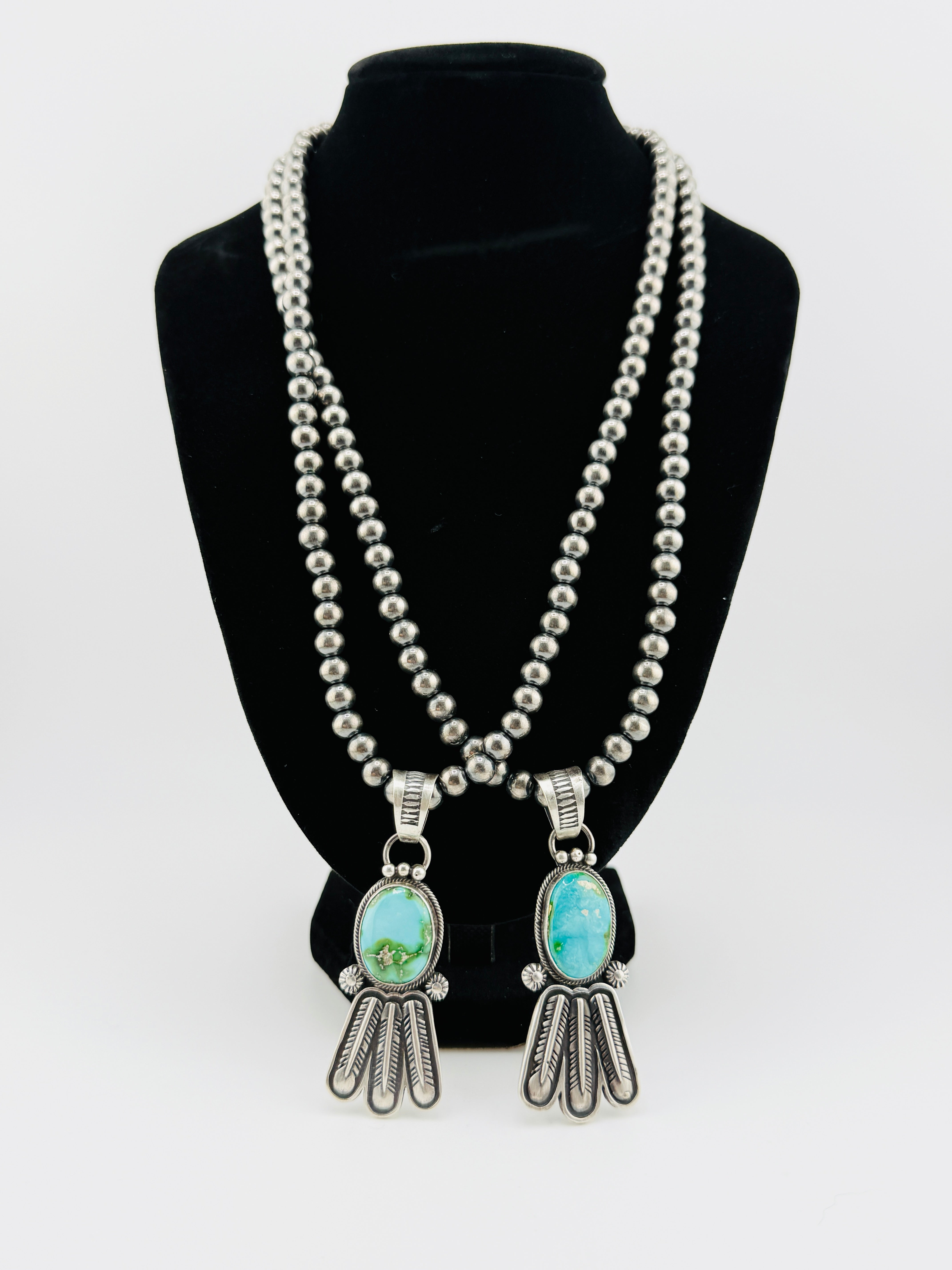 Necklace with turquoise pendants on a black bust against a white background