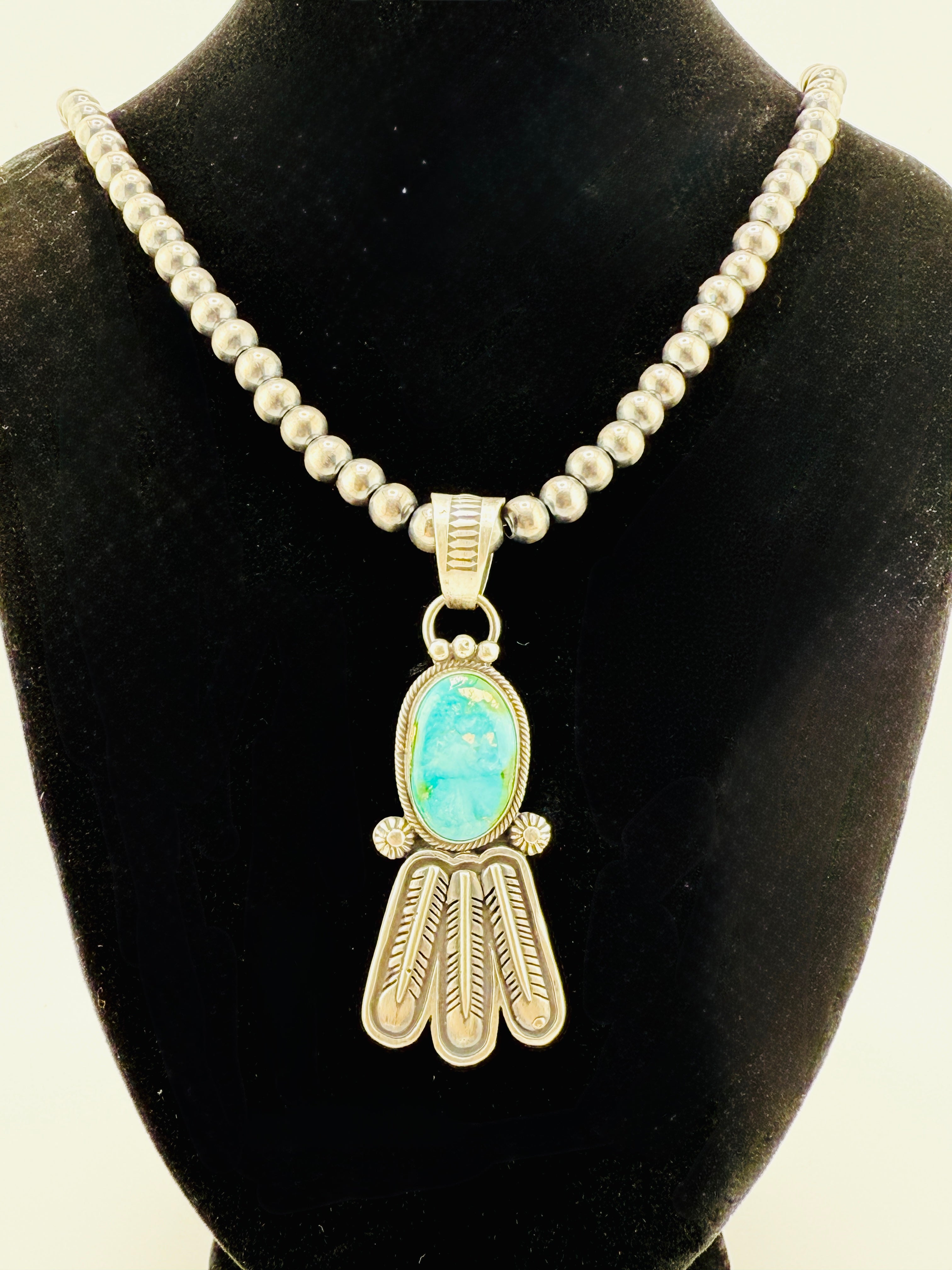 Necklace with a turquoise pendant on a black velvet stand