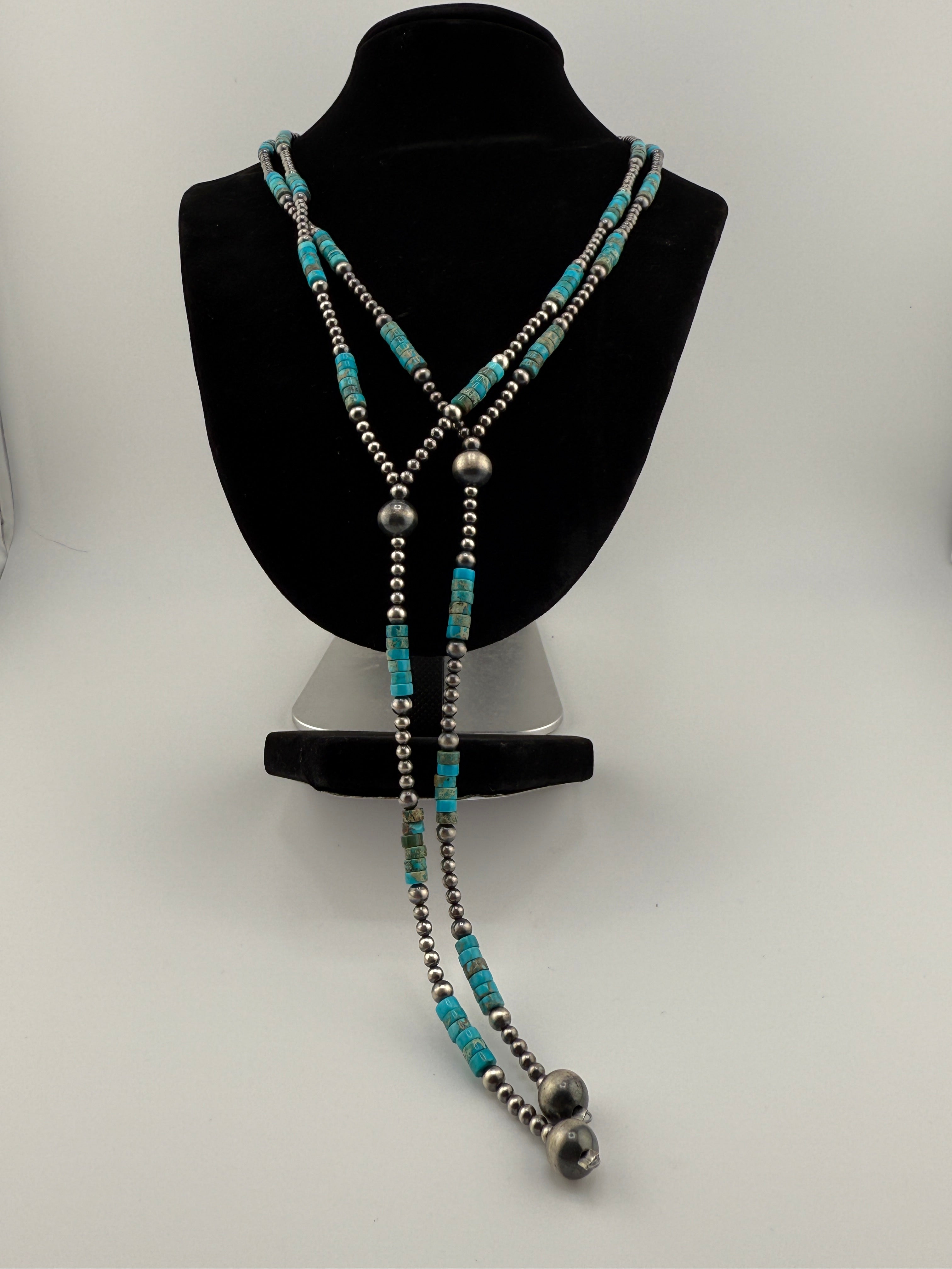 Turquoise and silver beaded necklace on a black jewelry display