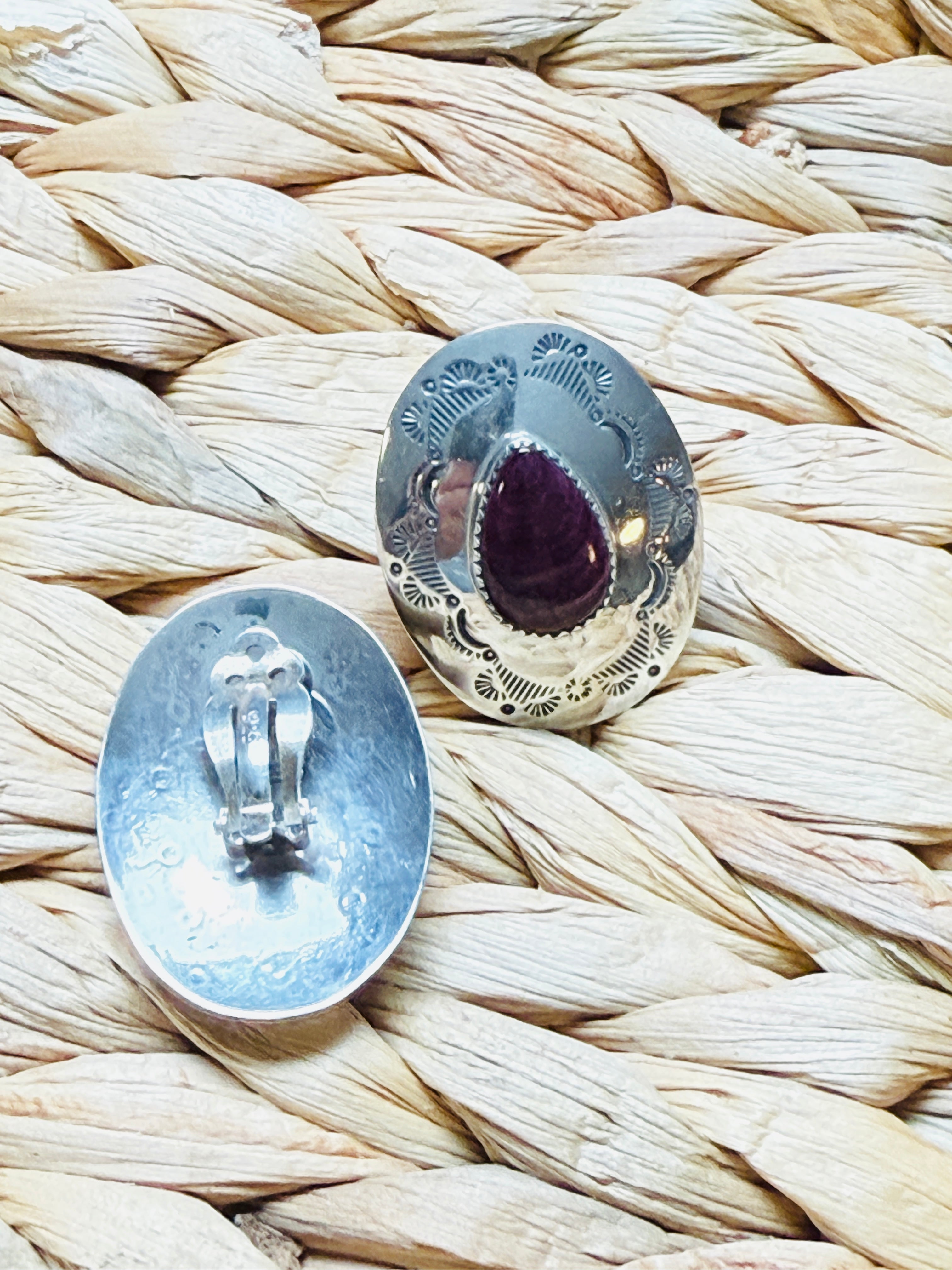Silver earrings with purple gemstones on a woven surface