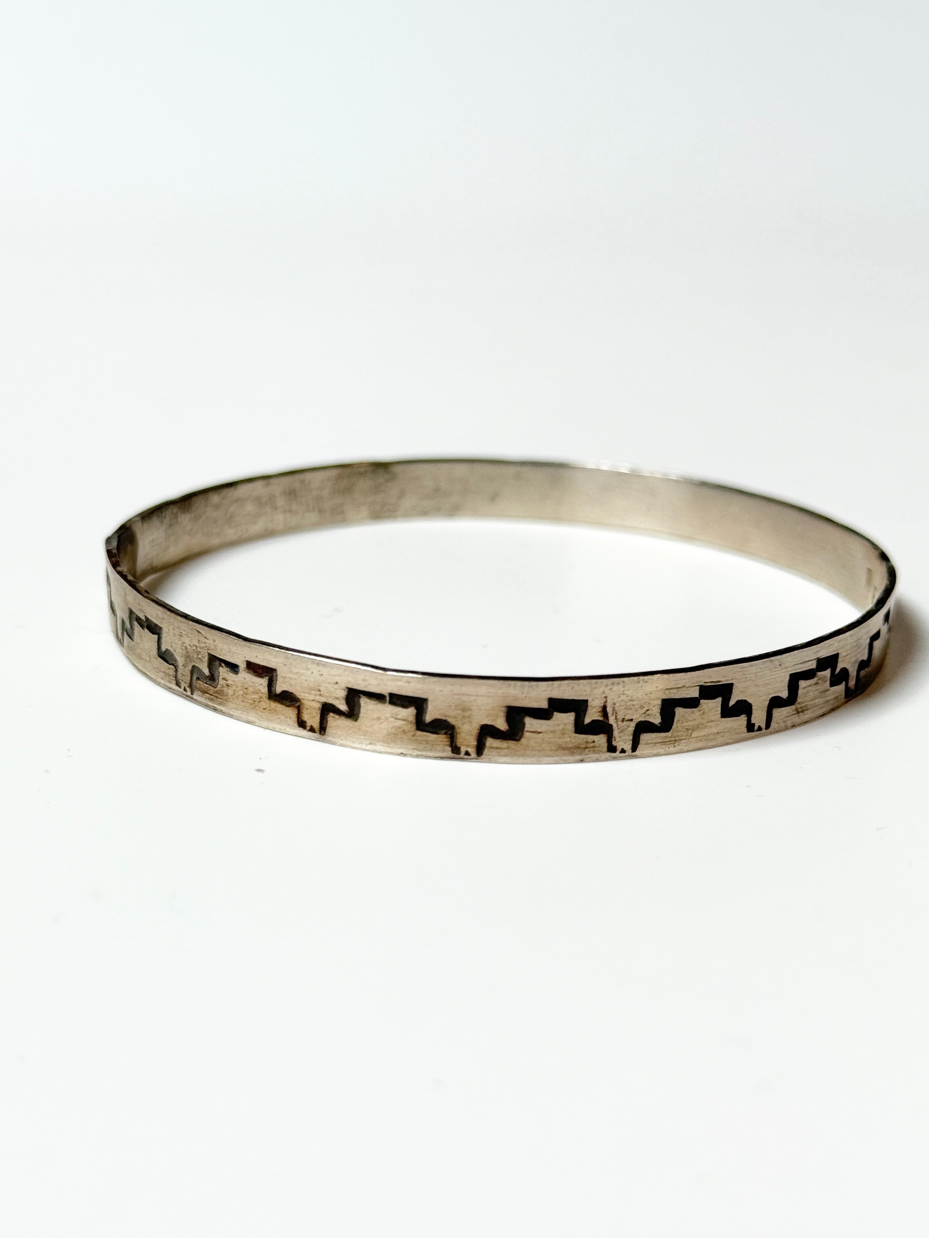 Silver bracelet with geometric pattern on a white background