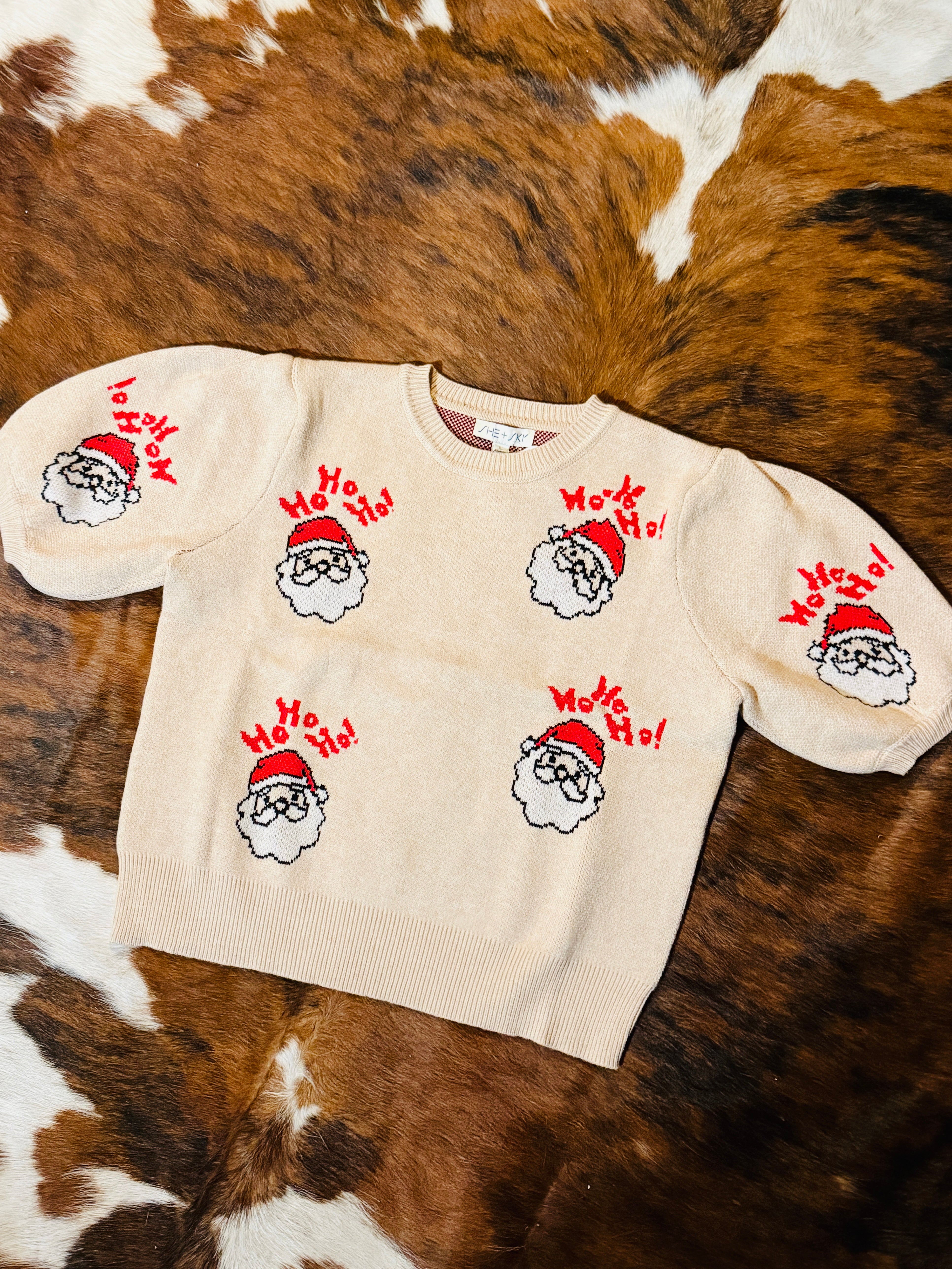 Beige sweater with Santa Claus designs on a brown and white fur background