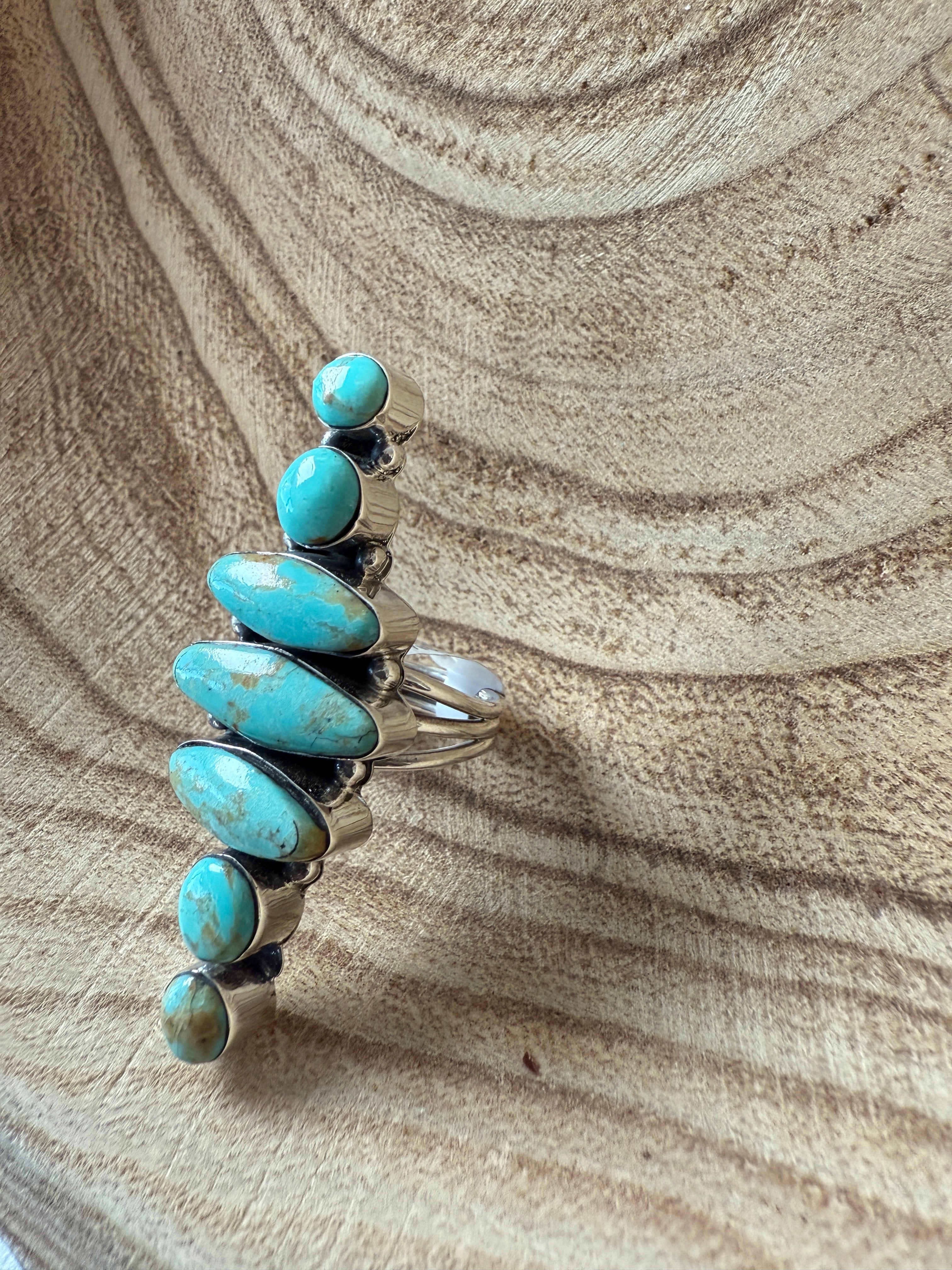 Silver bracelet with turquoise stones on a textured beige surface