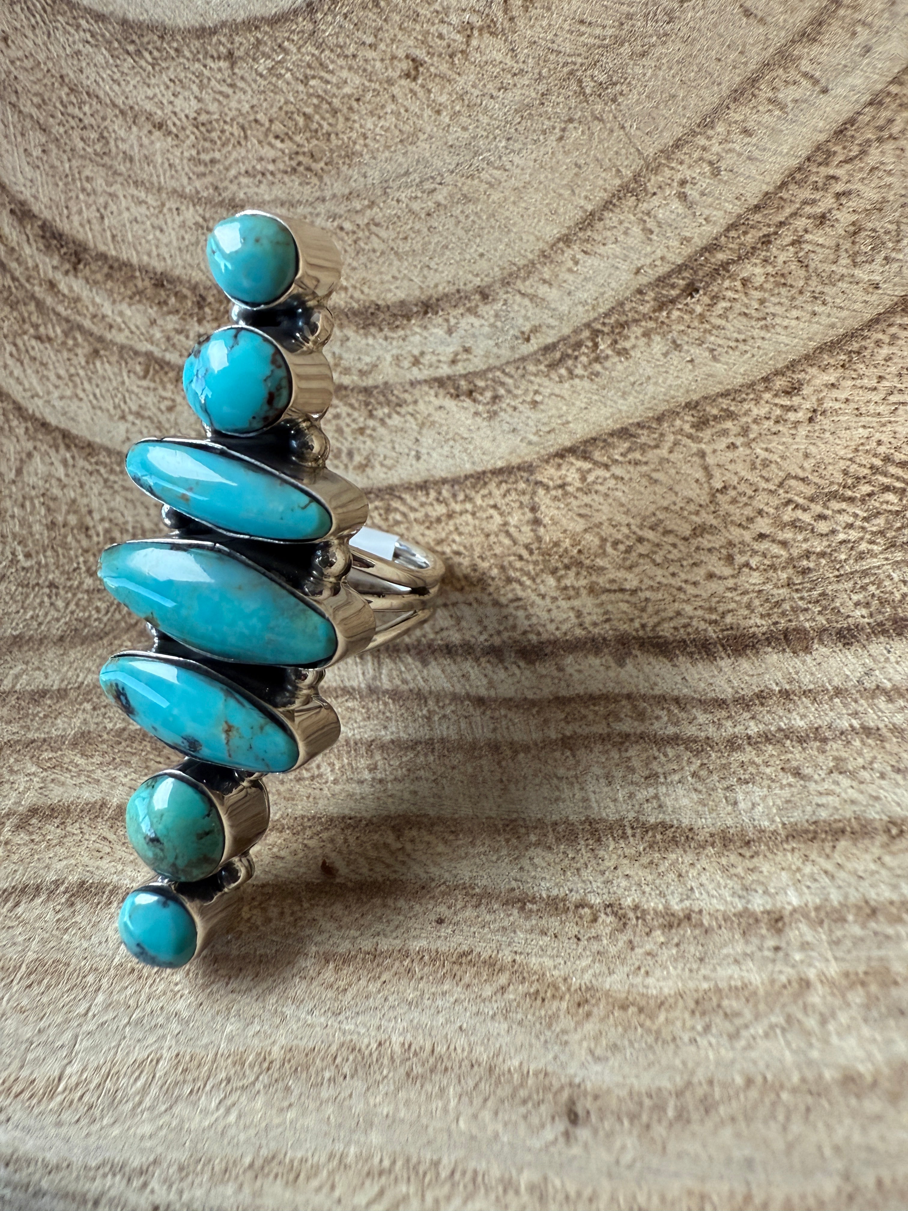 Silver ring with turquoise stones on a sandy background