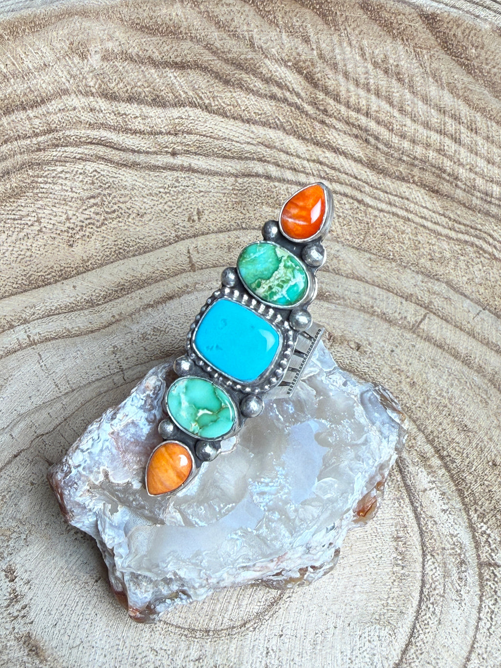 Jewelry with turquoise and orange stones on a textured stone surface